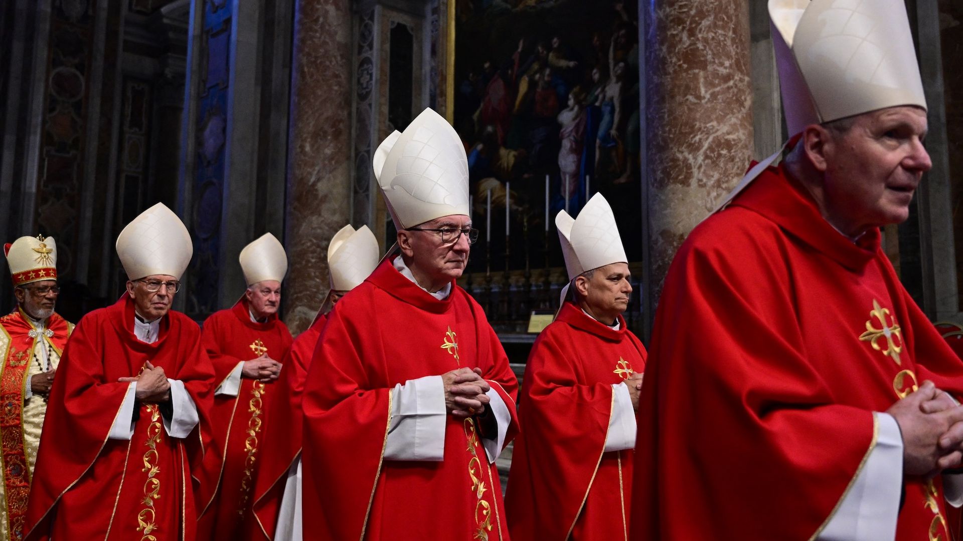Cardinals in red robes and white tall hats in a procession.