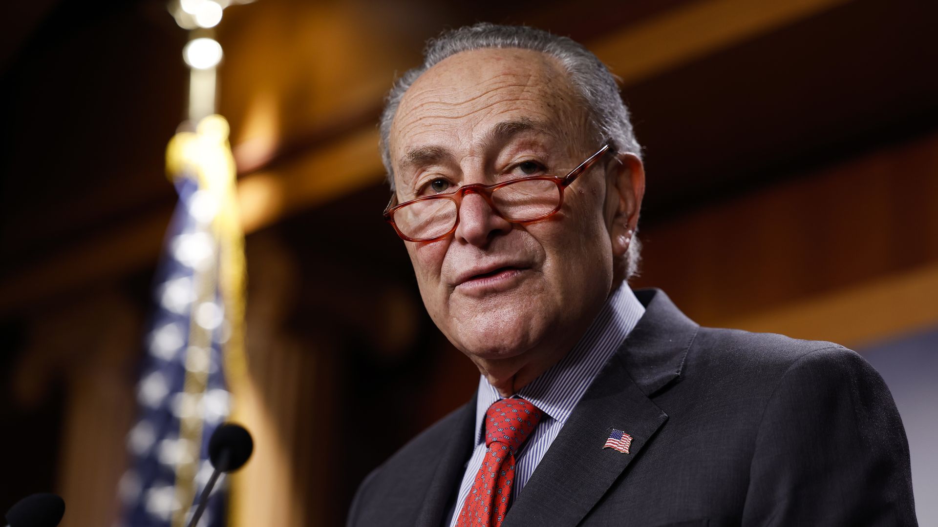 Chuck Schumer looks out over his lowered glasses at a press conference
