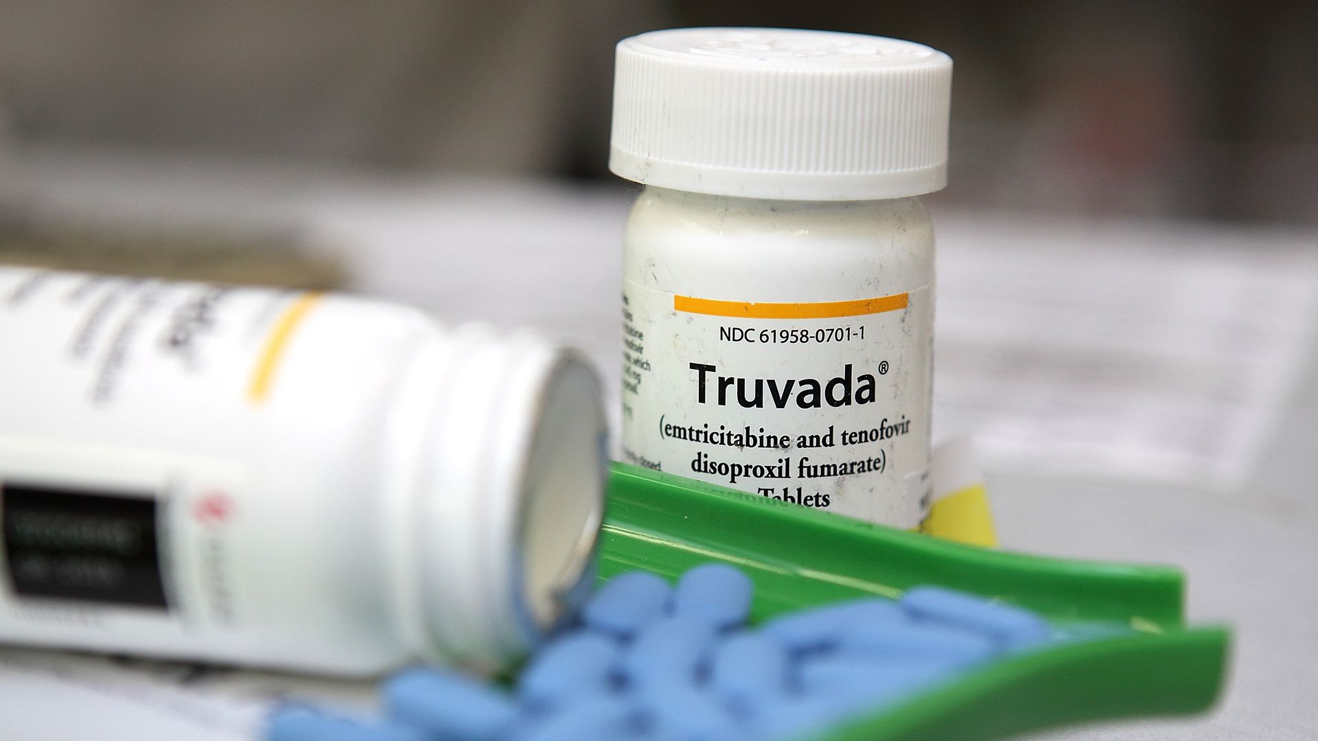 In this image, blue Truvada pills are being counted at a pharmacy. A pill bottle sits behind the counter. 