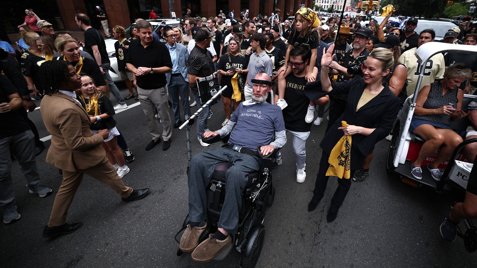 Steve Gleason leads a parade from his motorized wheelchair alongside Mayor Helena Moreno.
