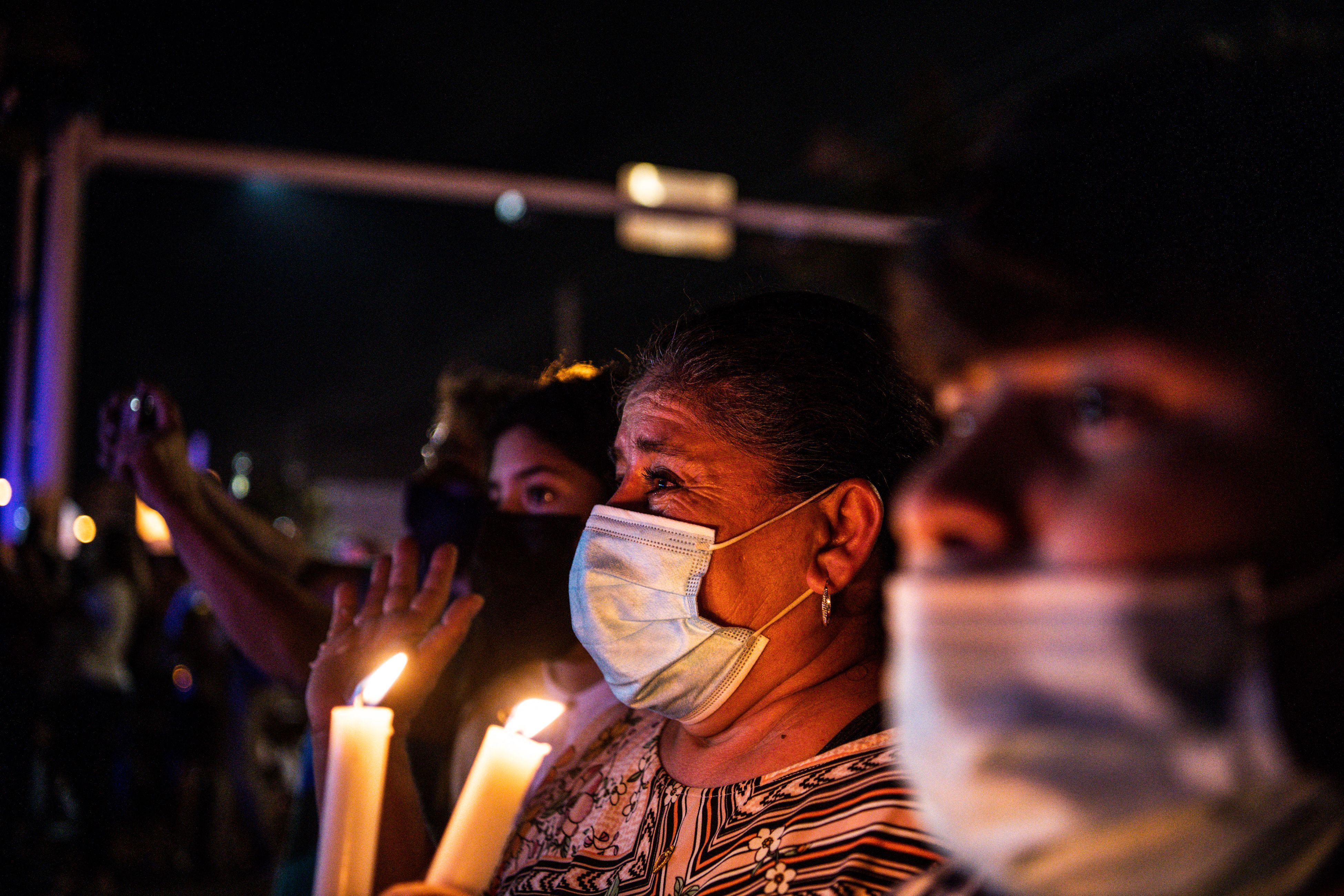 A woman holding candles cries as she watches the rest of the Champlain South tower being demolished by a controlled explosion in Surfside, Florida, north of Miami Beach, late on July 4