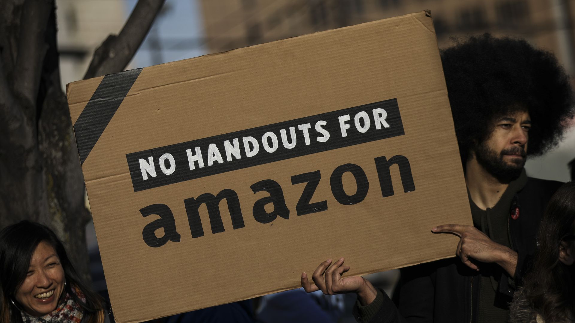 Protestor carries a sign saying no handouts for amazon