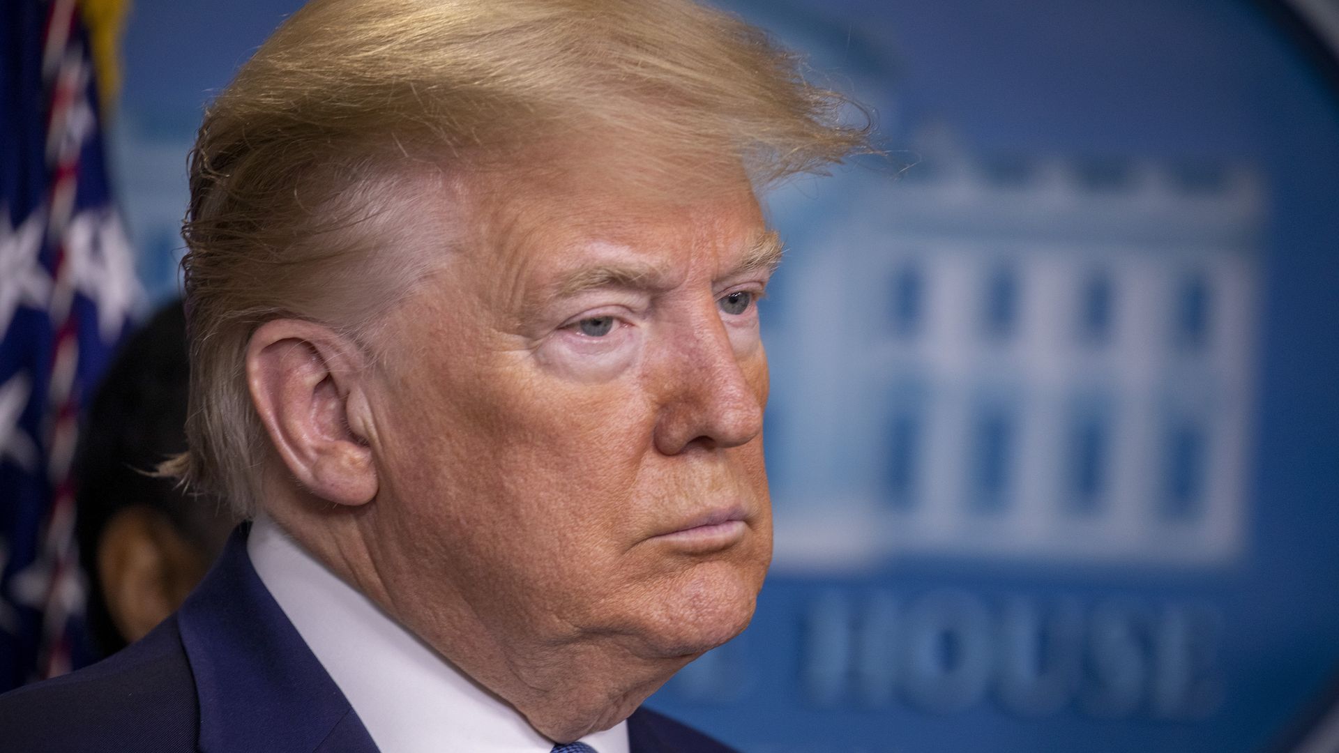 In this image, Trump stands in a suit