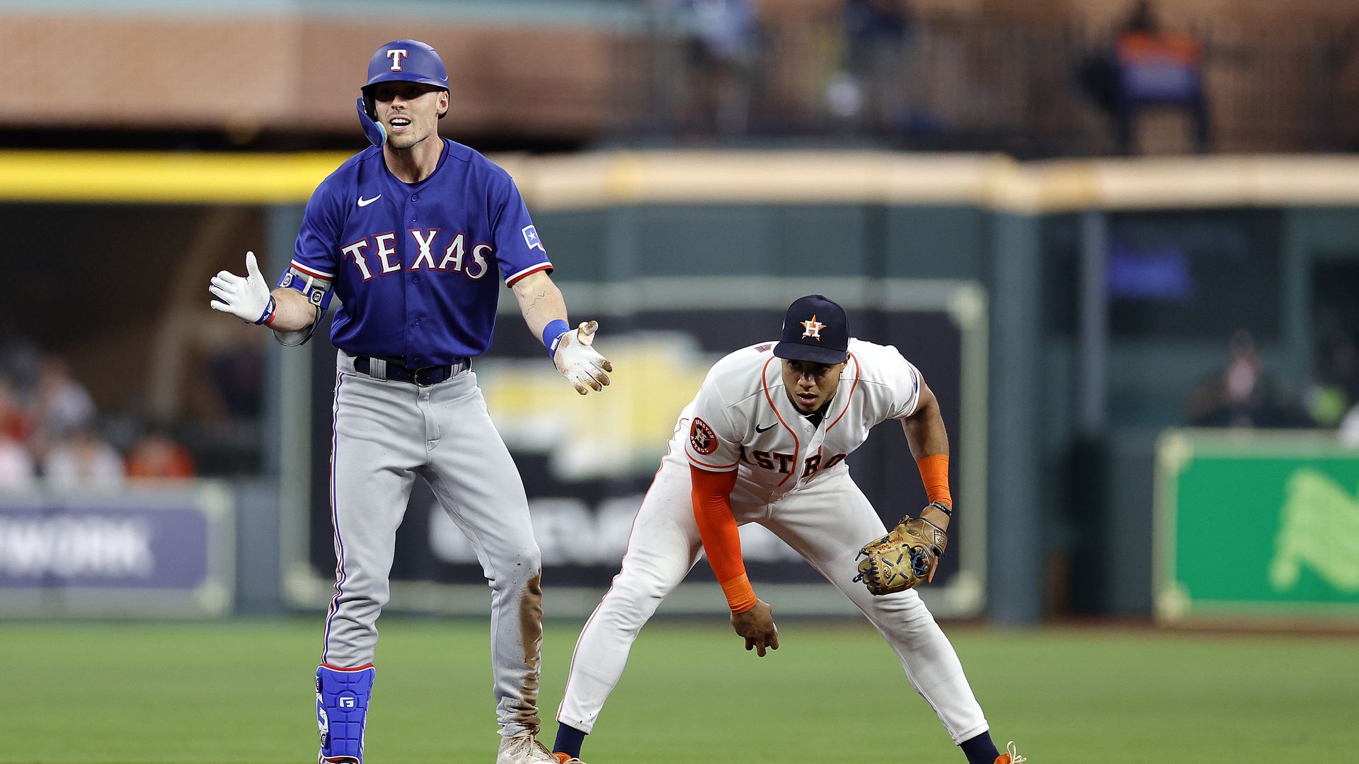 A Texas rangers player stands in a baseball park in Houston, next to an Astros player.