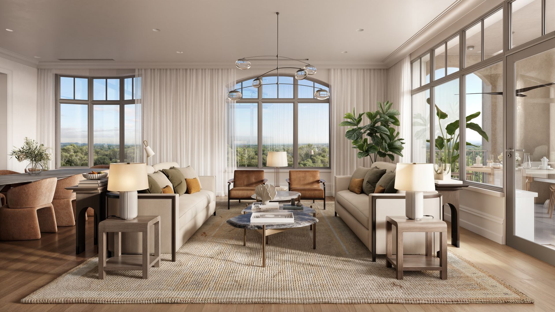 Bright, modern living room with large windows, two beige sofas with green and orange pillows, two brown leather chairs, wood floors, neutral rug, lamps, plants, and a round coffee table.