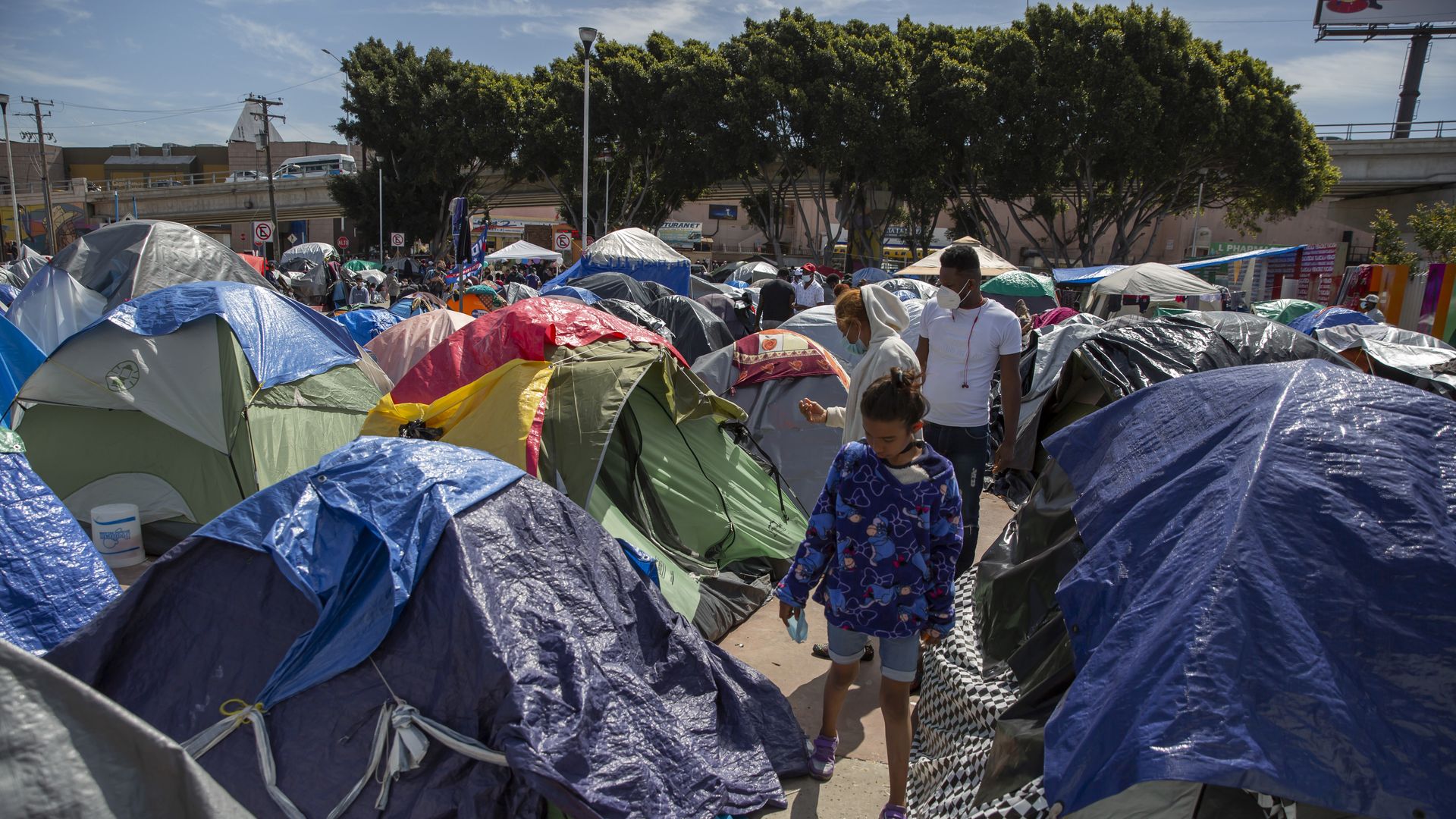 A child walks through tents at a migrant camp on the grounds of the National Institute for Migration near the "El Chaparral" border crossing.