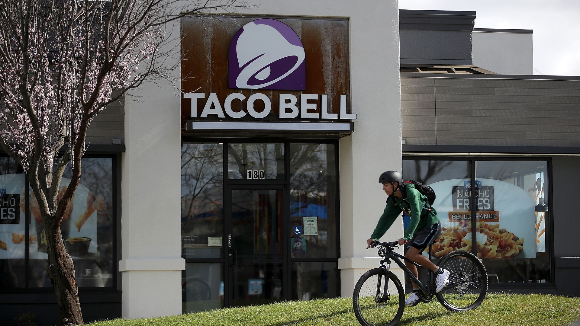 A customer rides his bike in front of Taco Bell.