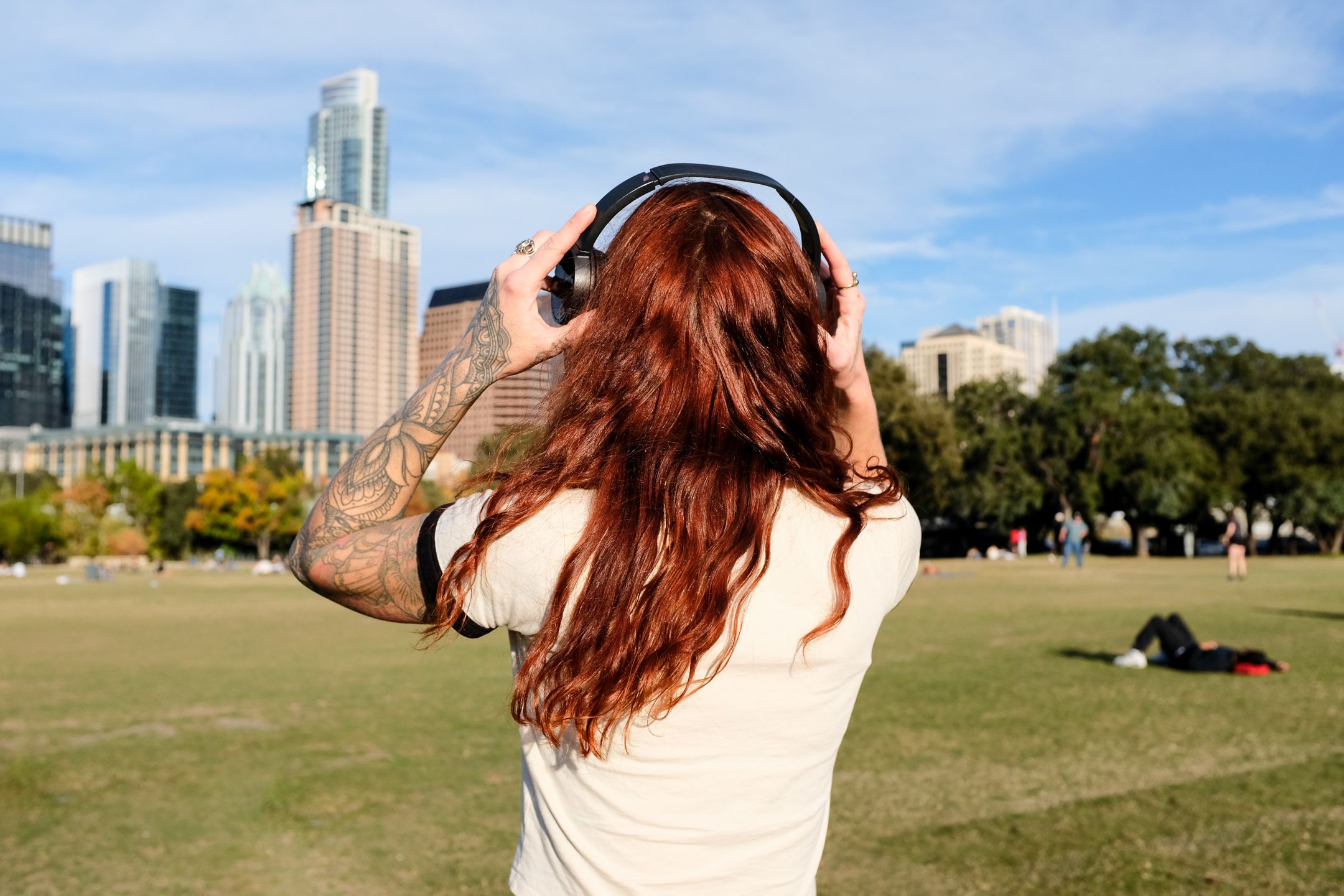 A photo of a women holding a pair of headphones and looking at a skyline.