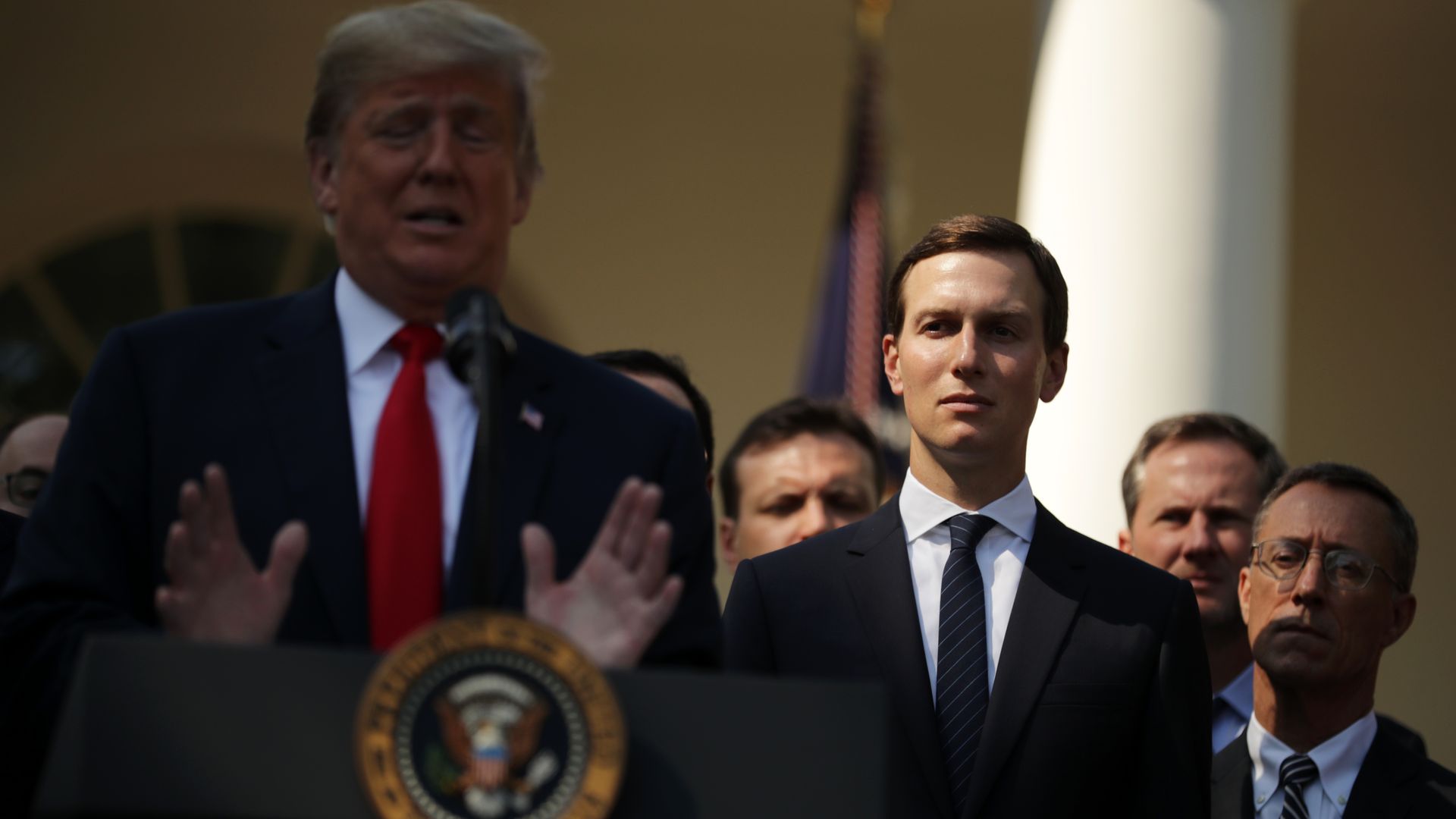 Jared Kushner stands behind Donald Trump.