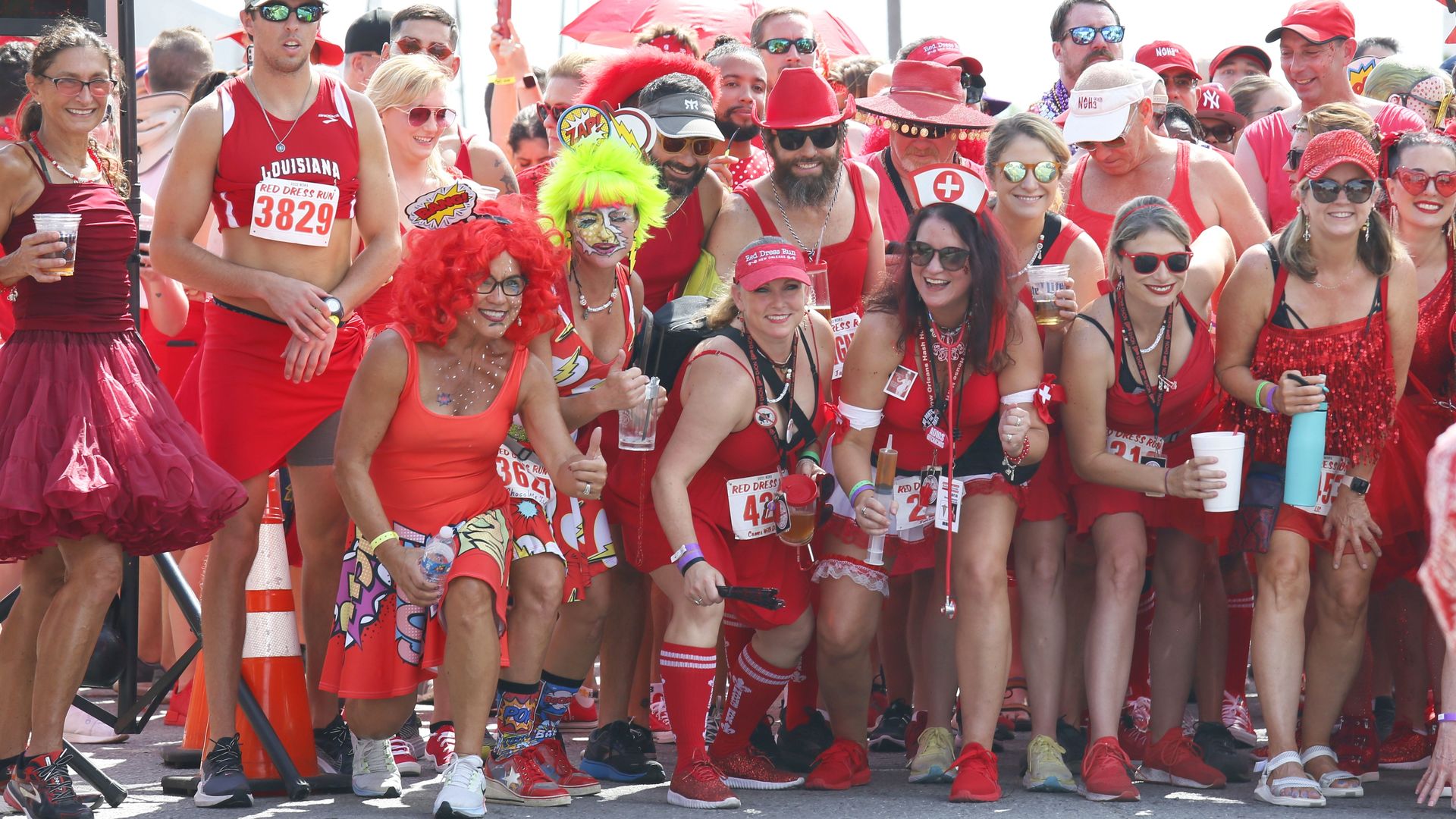 Dozens of people get ready to run at a starting line. They're all wearing red.
