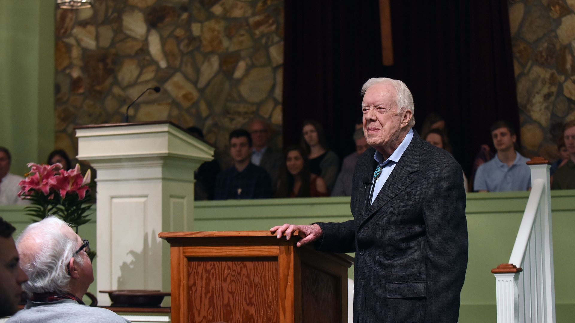 Jimmy Carter stands in front of a podium inside a church 