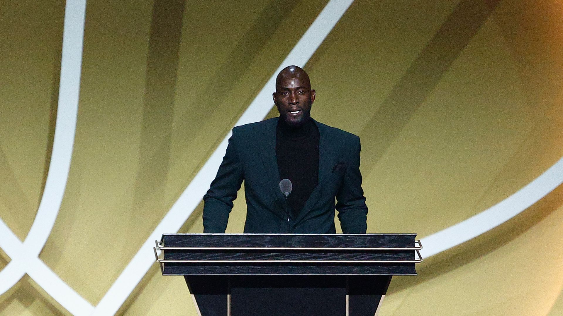 Kevin Garnett wears a black turtle neck under a suit and gives his Hall of Fame speech