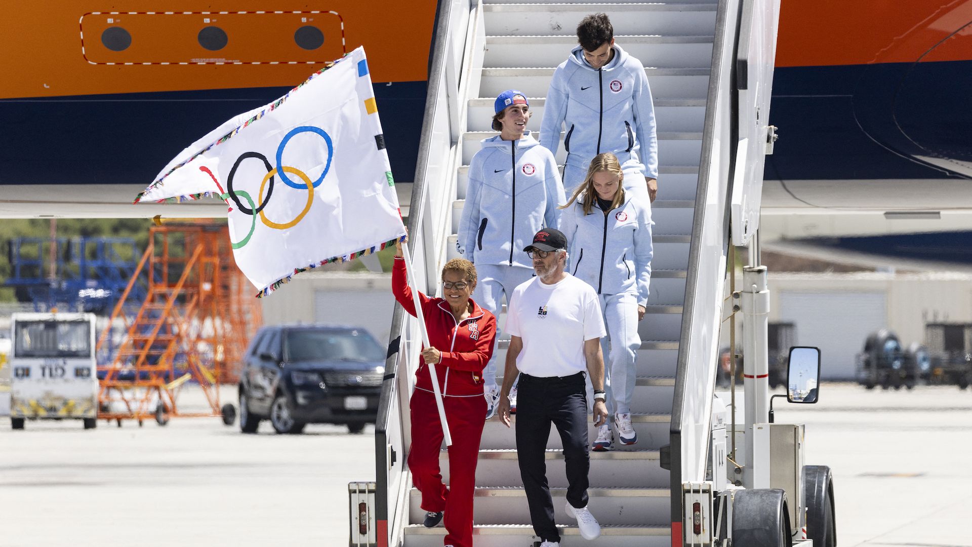 Tate Carew with LA Mayor Karen Bass carrying the Olympic flag off a plane from Paris to Los Angeles.