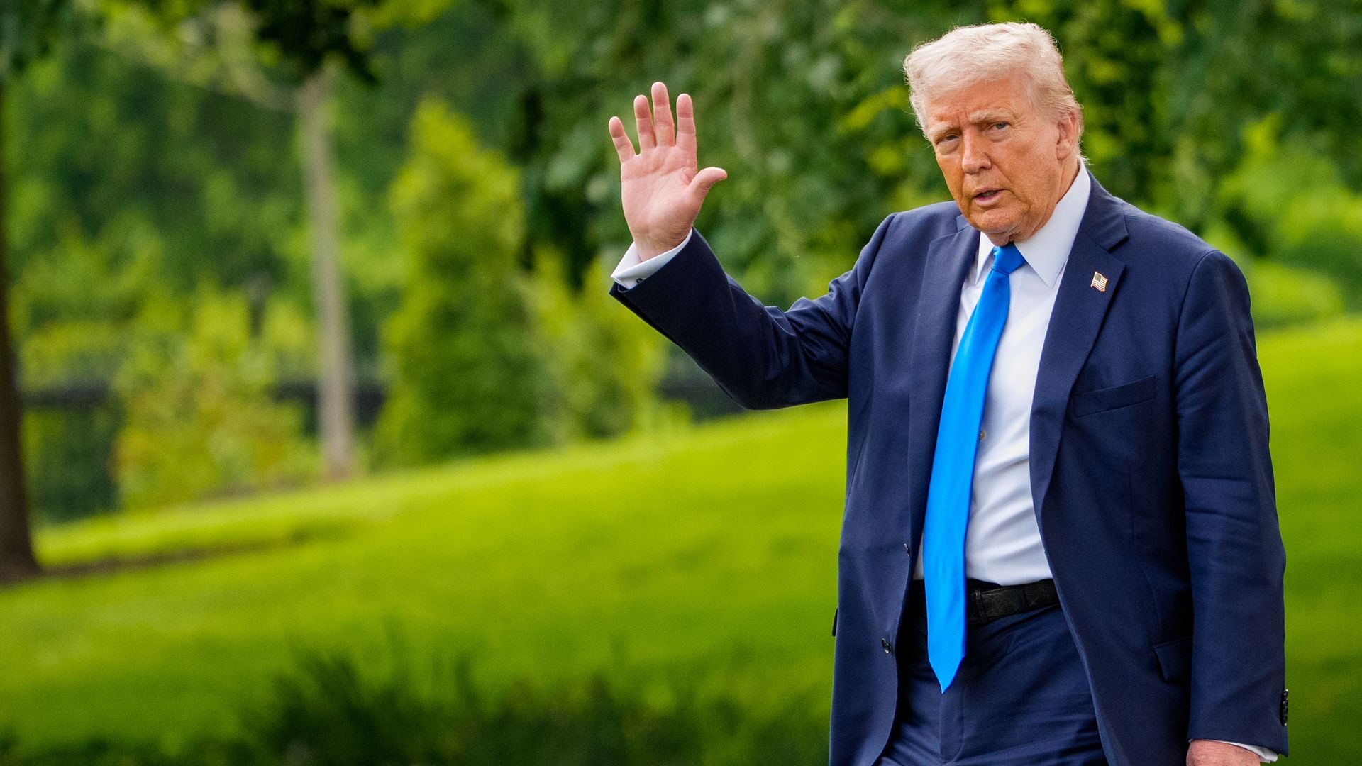 Trump waves to cameras as he walks outside