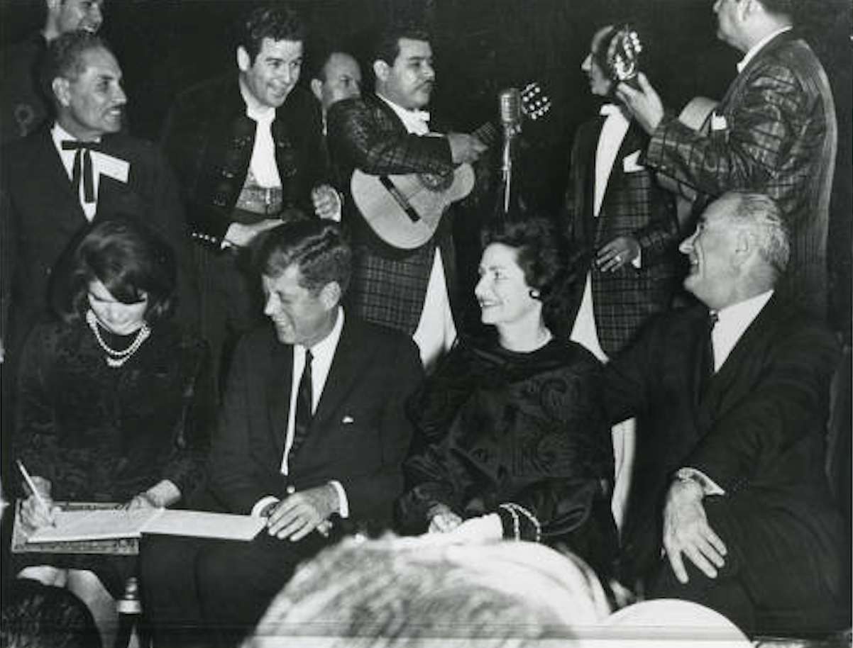 First Lady Jacqueline Kennedy, President John F. Kennedy, Lady Bird Johnson and Vice President Lyndon Johnson sit in front of mariachis in Houston the night before the president is assassinated. 