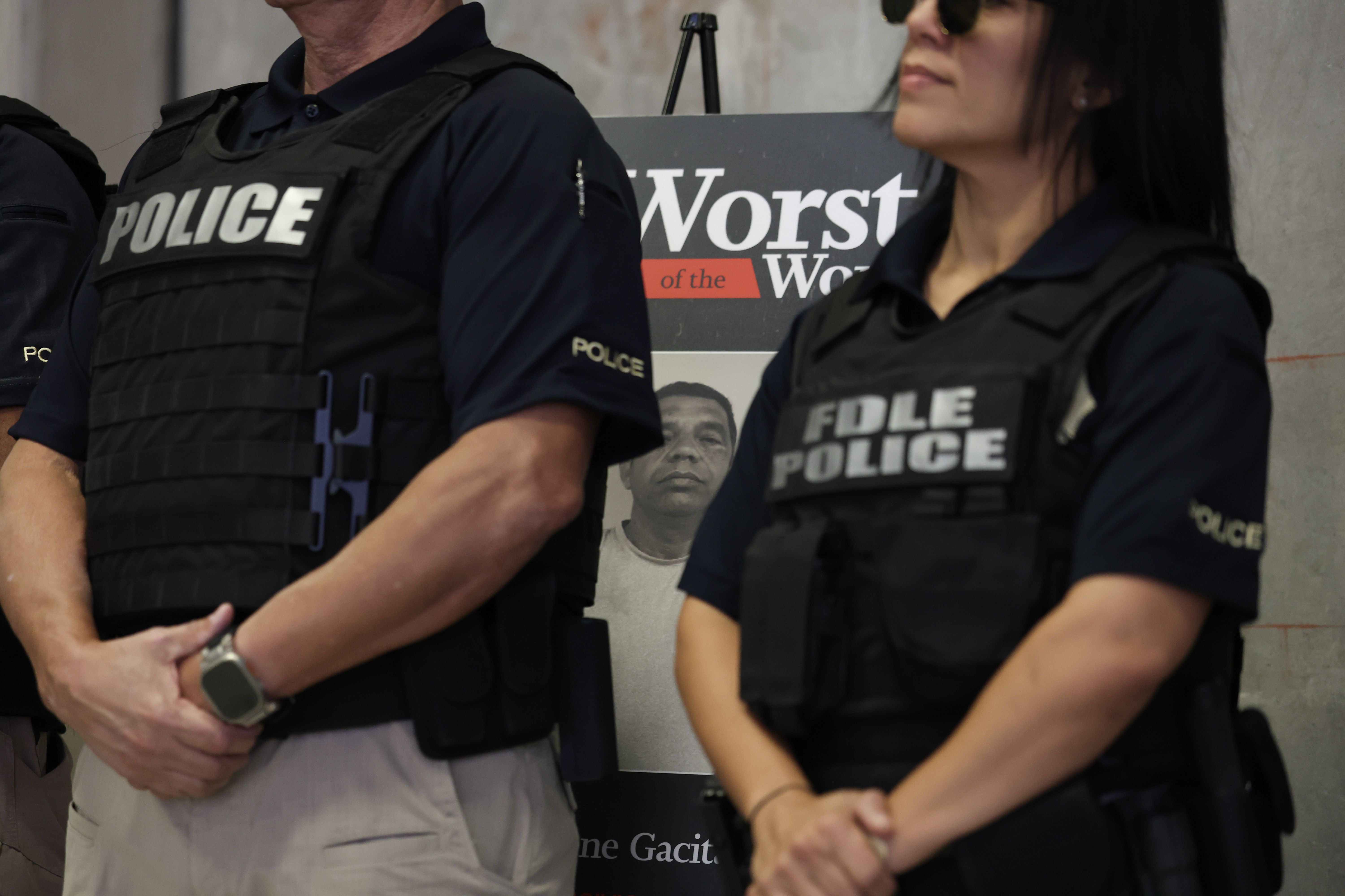 MIRAMAR, FLORIDA - NOVEMBER 13: Florida Department of Law Enforcement officers stand near a picture of an alleged criminal alien during a press conference at the ICE, Enforcement and Removal Operations building on November 13, 2025 in Miramar, Florida. Officials announced the results of an immigrati