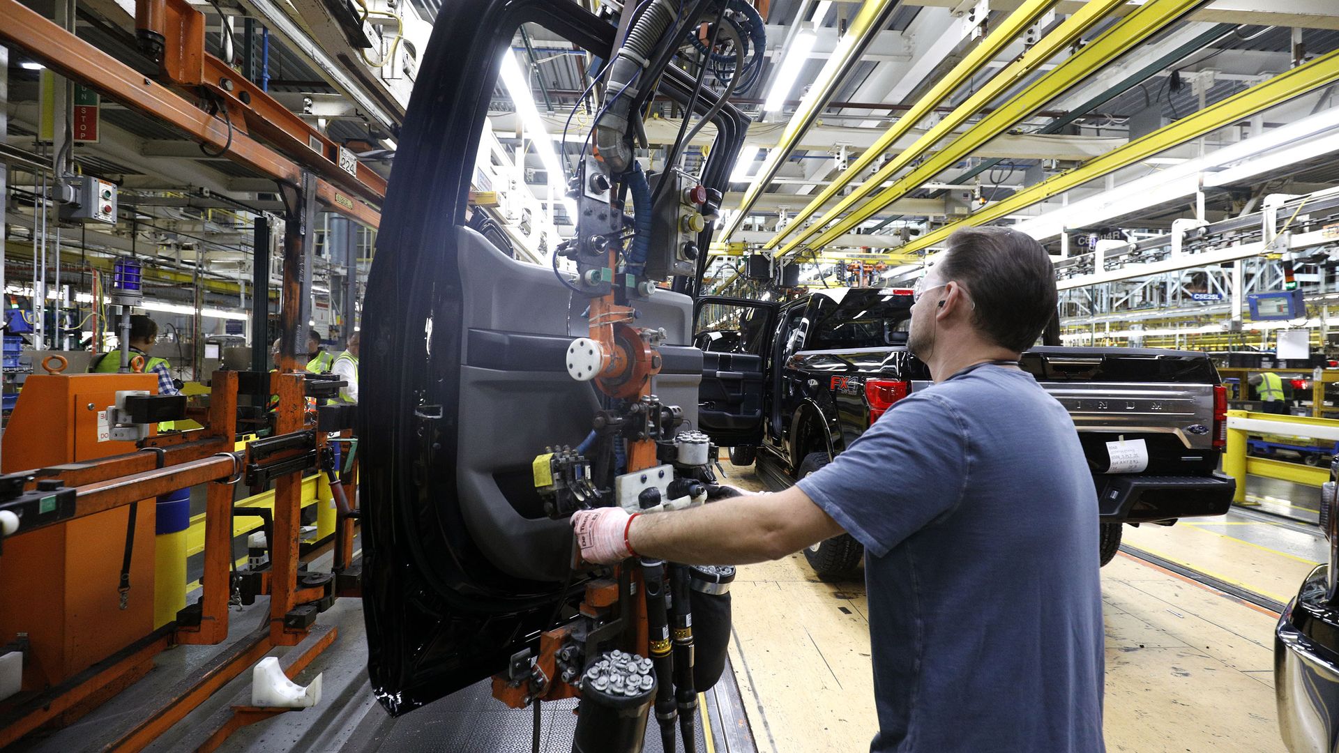 A man works on a truck door in a factory