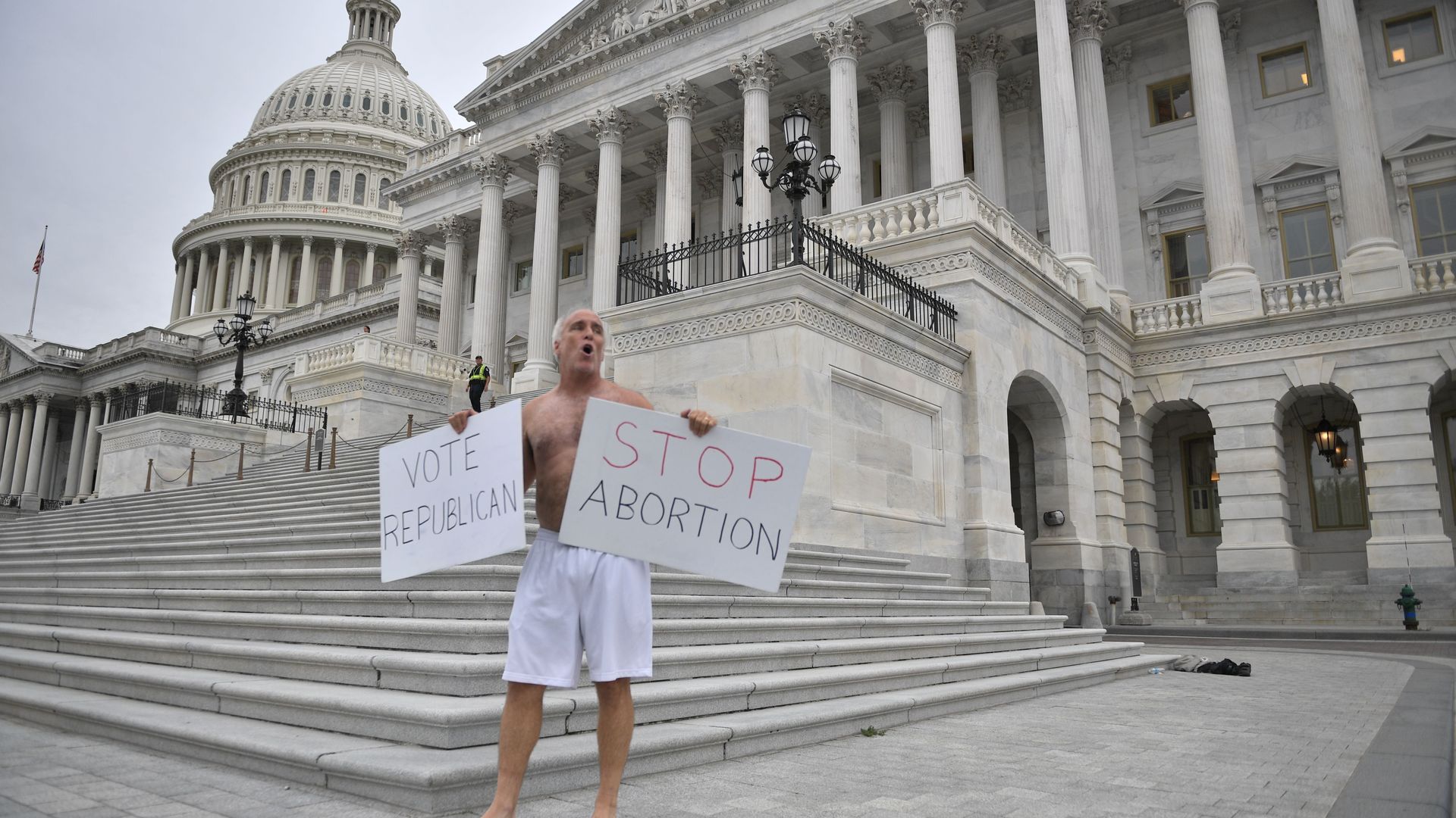 MAn protesting in front of the U.S. capitol saying stop abortion vote republican 