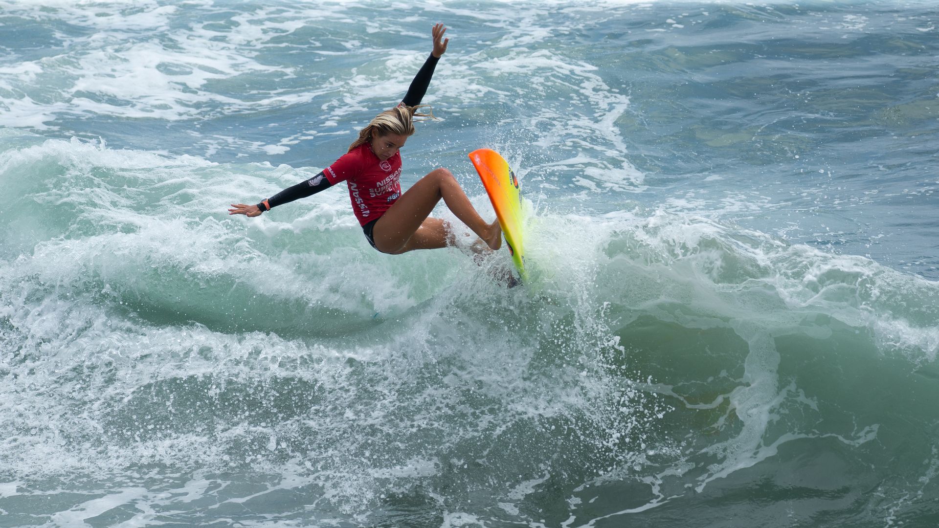 A female surfer cuts back on a wave.