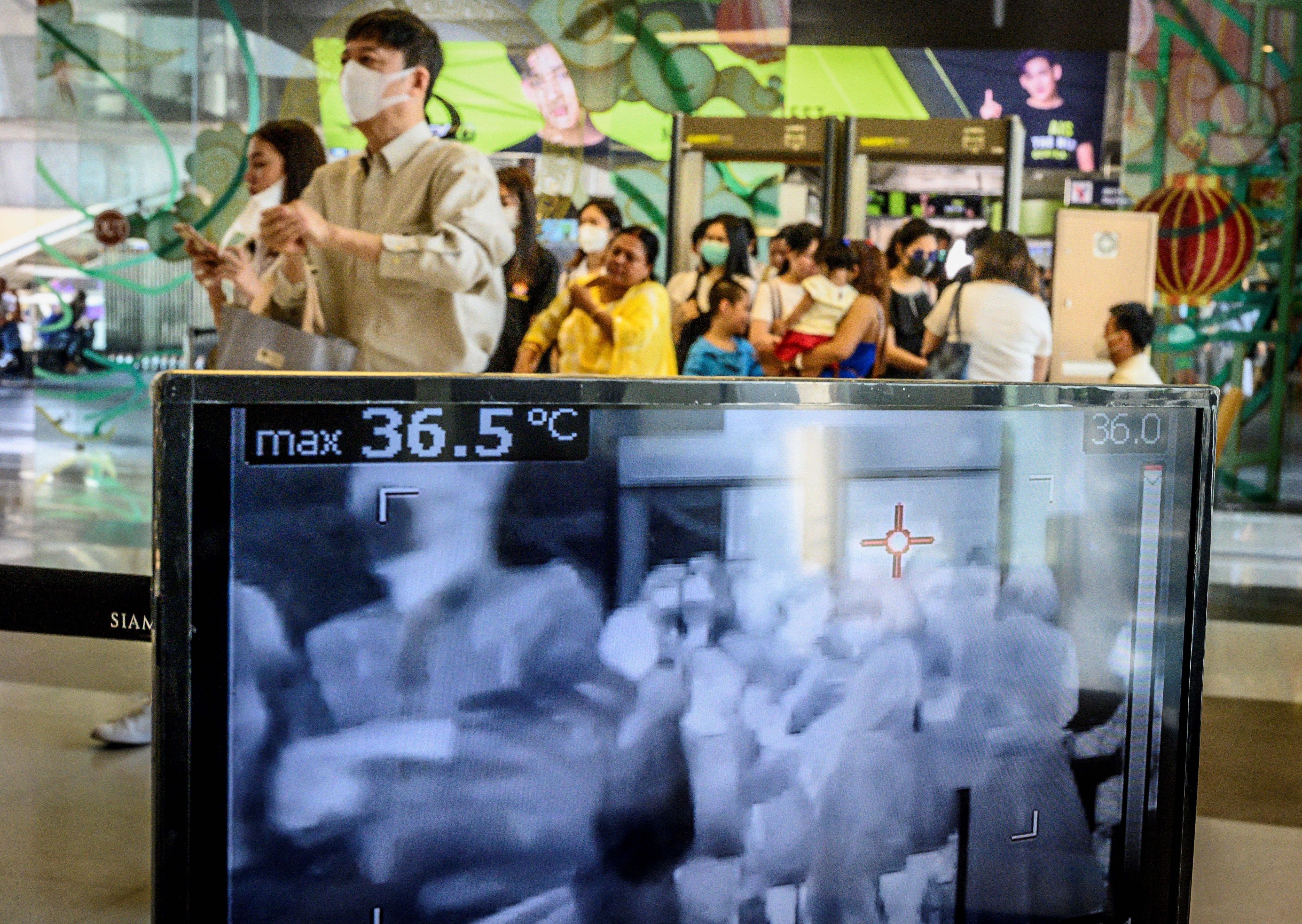  People with protective face masks pass in front of a thermal scanner as they enter a shopping mall in Bangkok on January 29