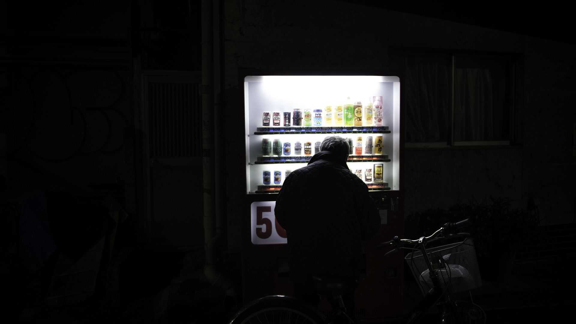 A man silhouetted in front of a vending machine. 