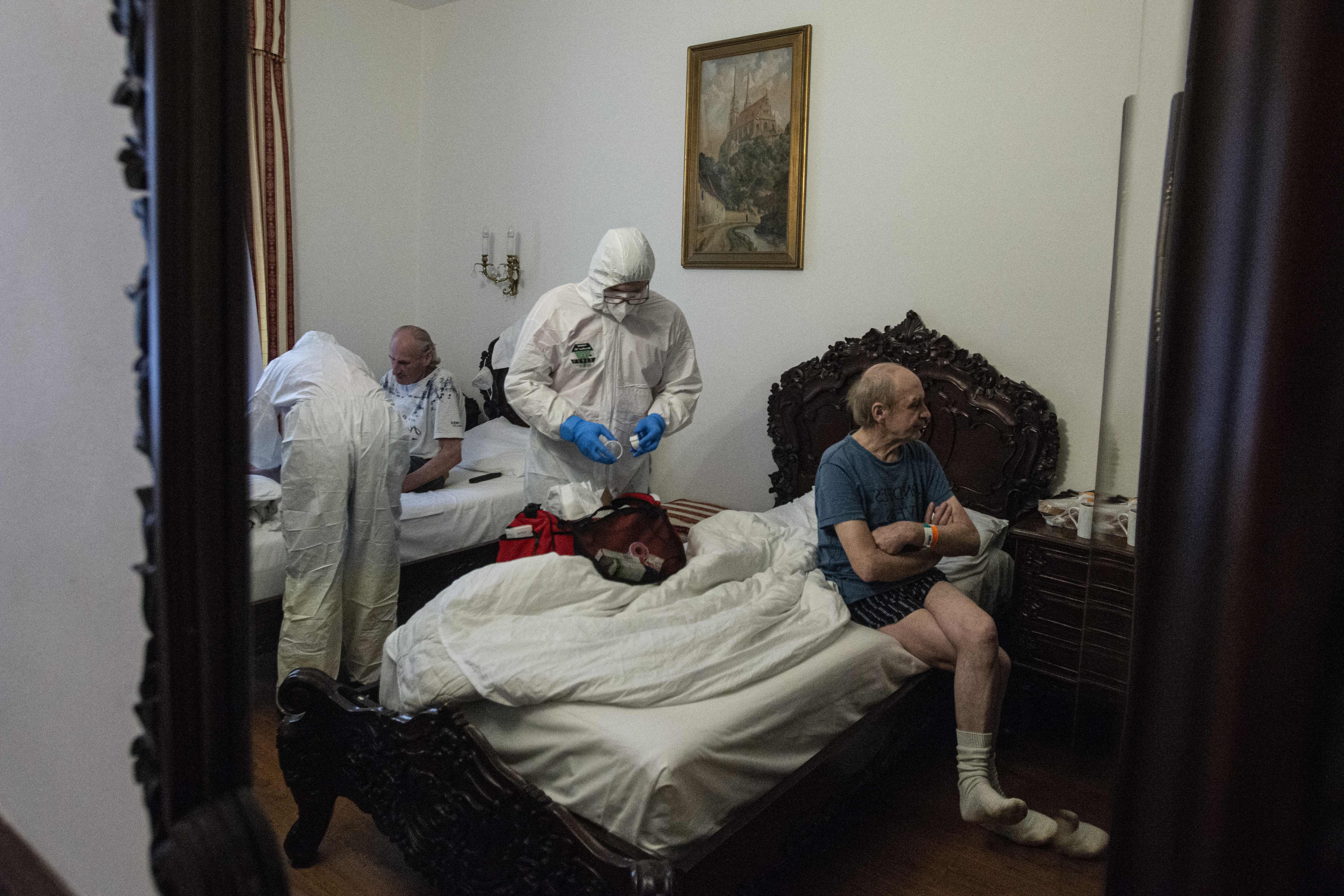 Healthcare workers in personal protective equipment (PPE) look after a homeless coronavirus patients, in a hotel room in Prague on March 8