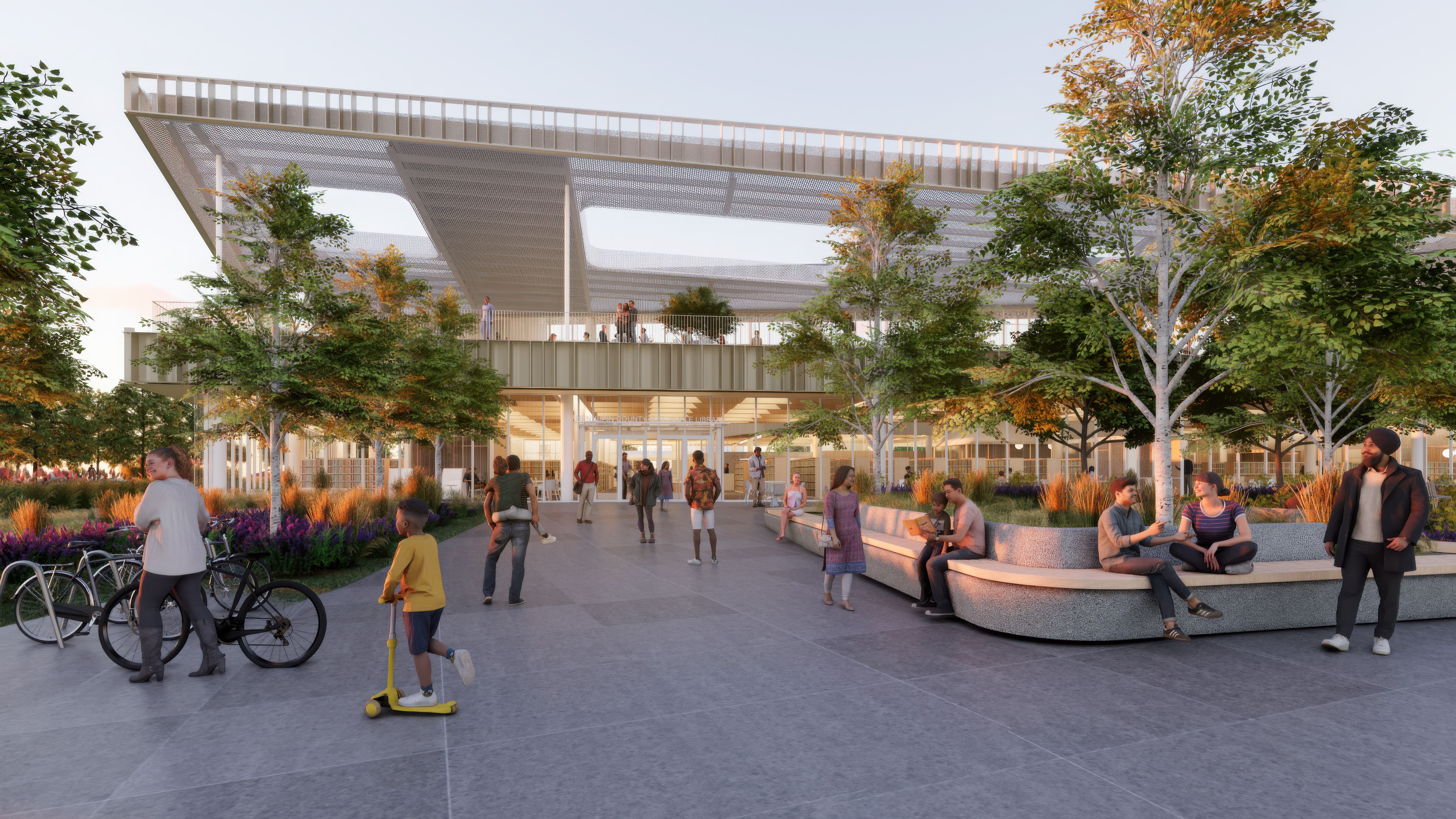 People outside a modern building with large windows and a mesh canopy roof, surrounded by trees, greenery, and benches at sunset, showing a lively community space.