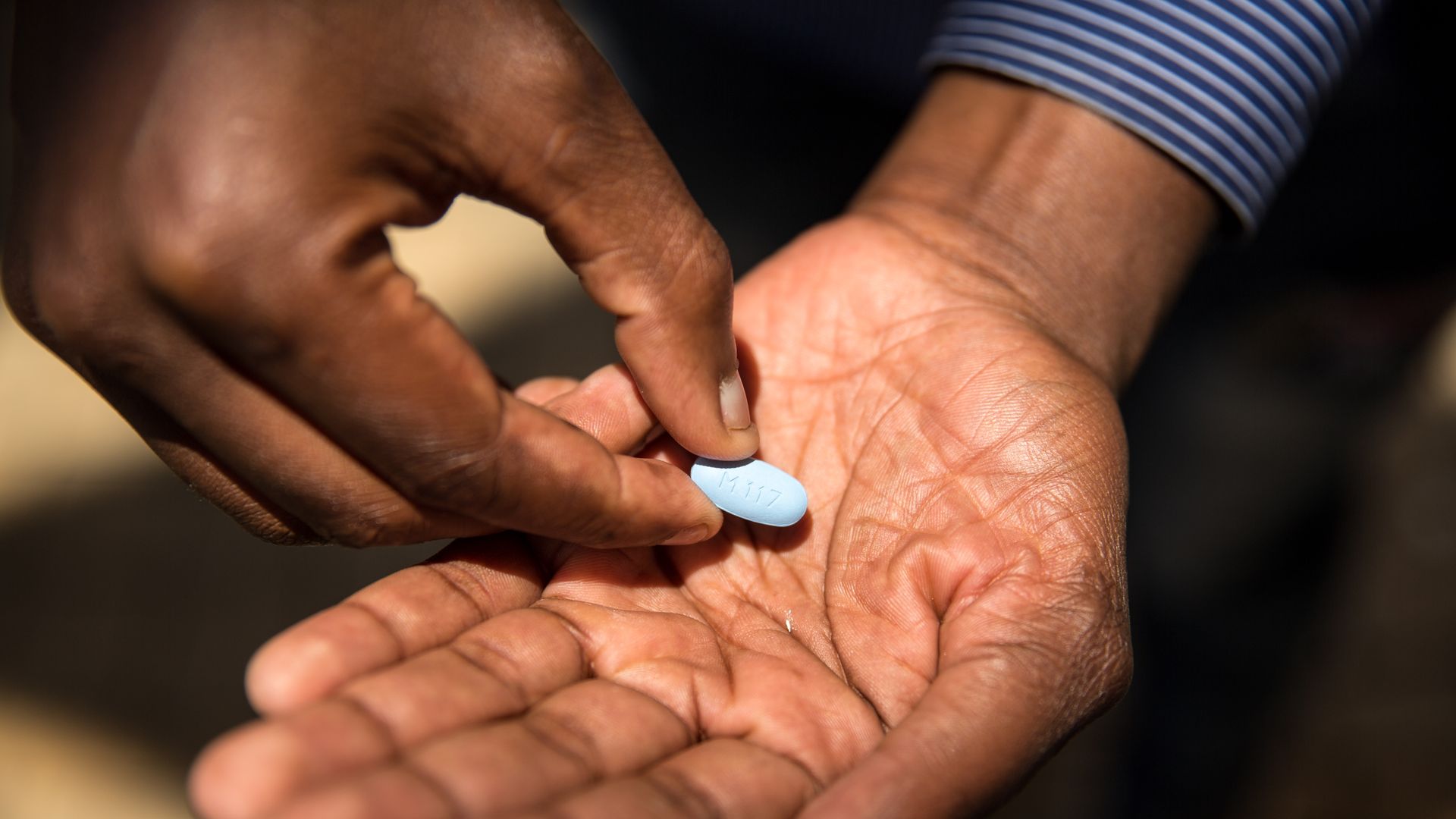 A man's hands holding one big blue pill, PrEP