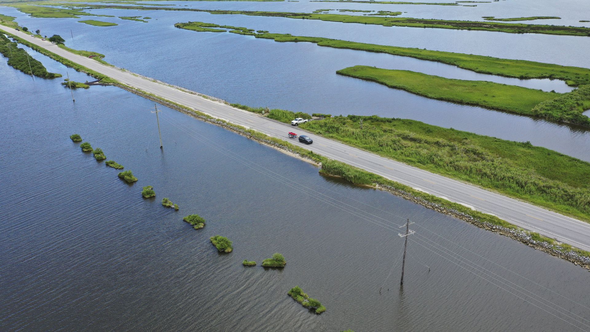 Photo shows a road surrounded by water.