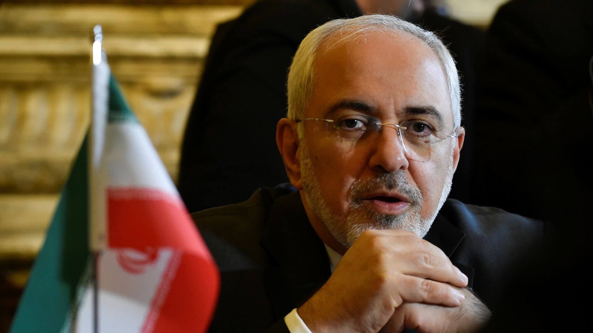 Zarif sits next to an Iranian flag
