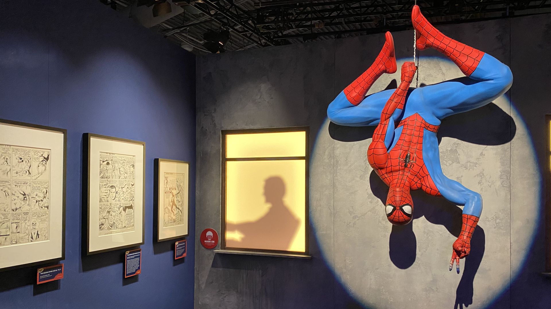 A Spider-Man prop hangs upside down, displayed by a spotlight