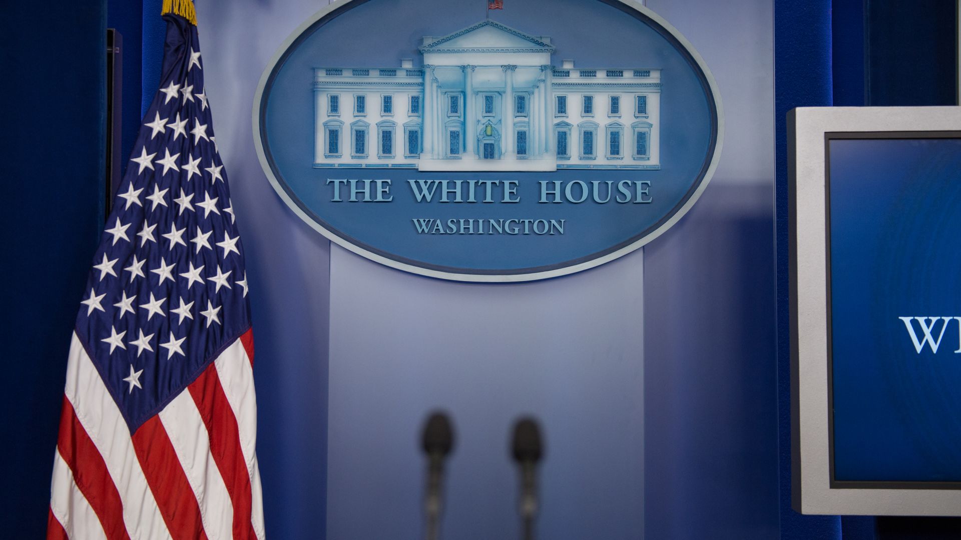 White House logo hangs behind the press secretary's podium in the White House press briefing room.