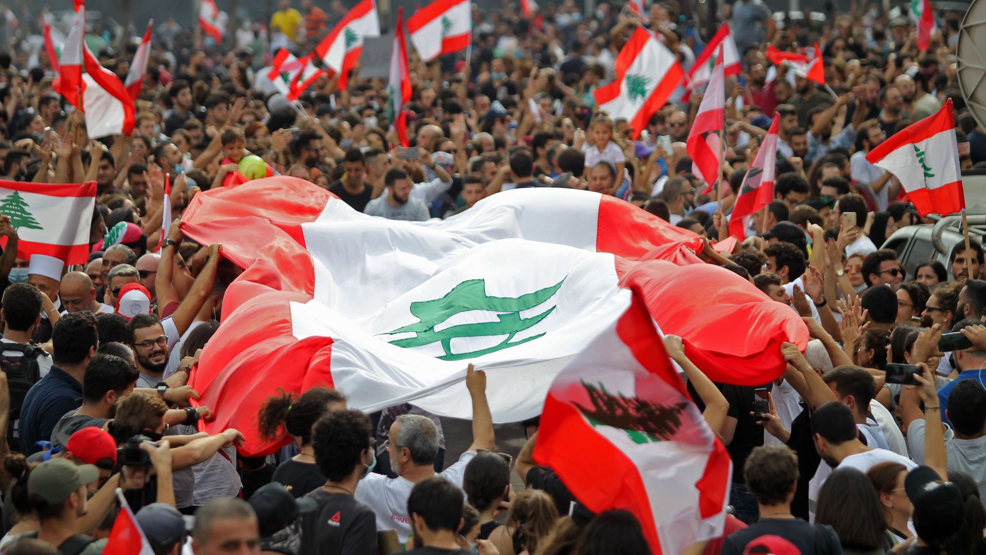 Lebanese protesters with a large Lebanese flag 