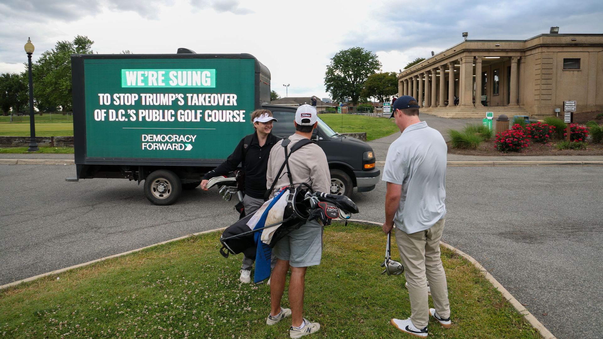 A Democracy Forward billboard truck drives in front of golfers at East Potomac Golf Course. 