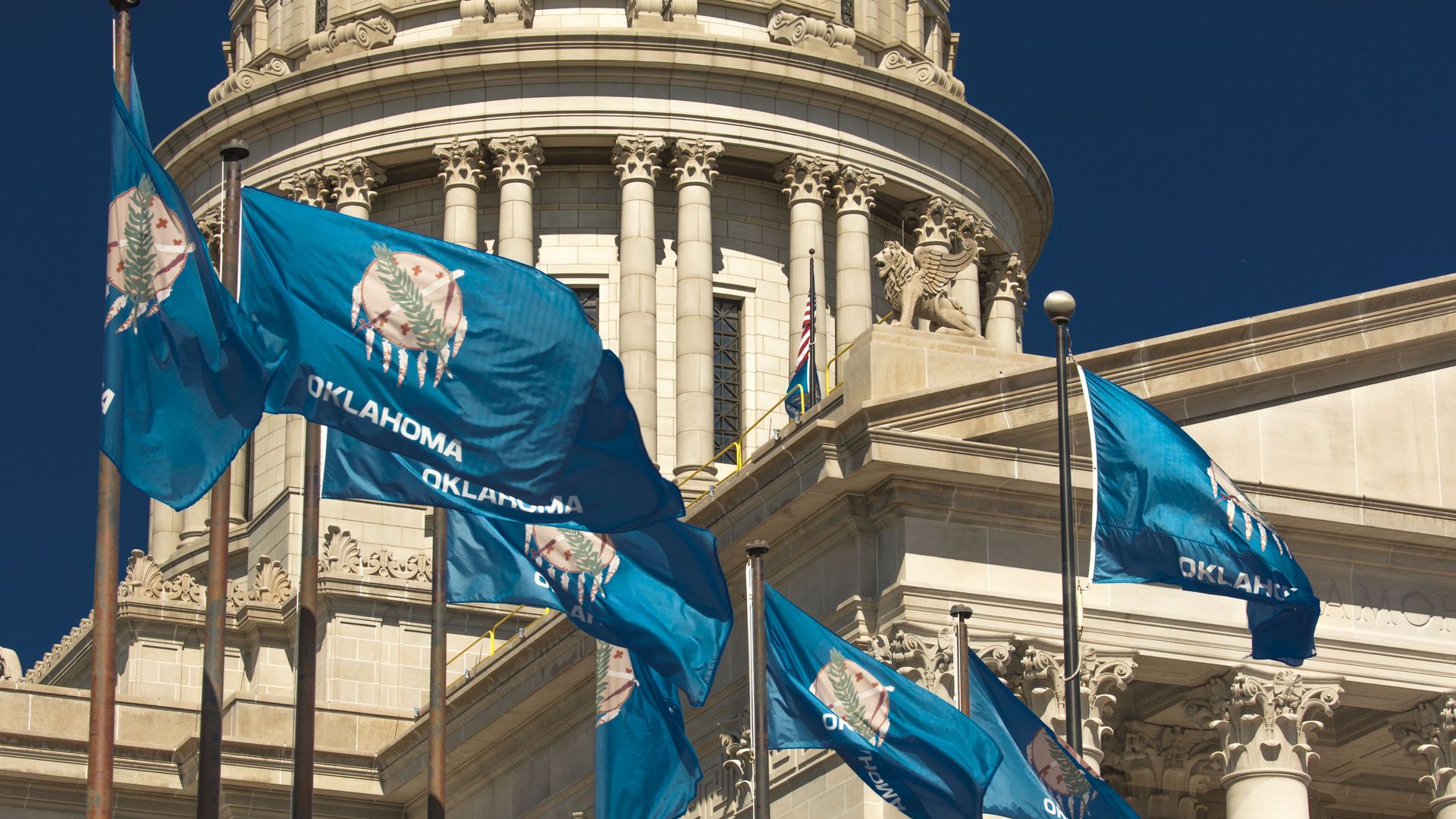 Photo of Oklahoma stage flags flying next to the state capitol building