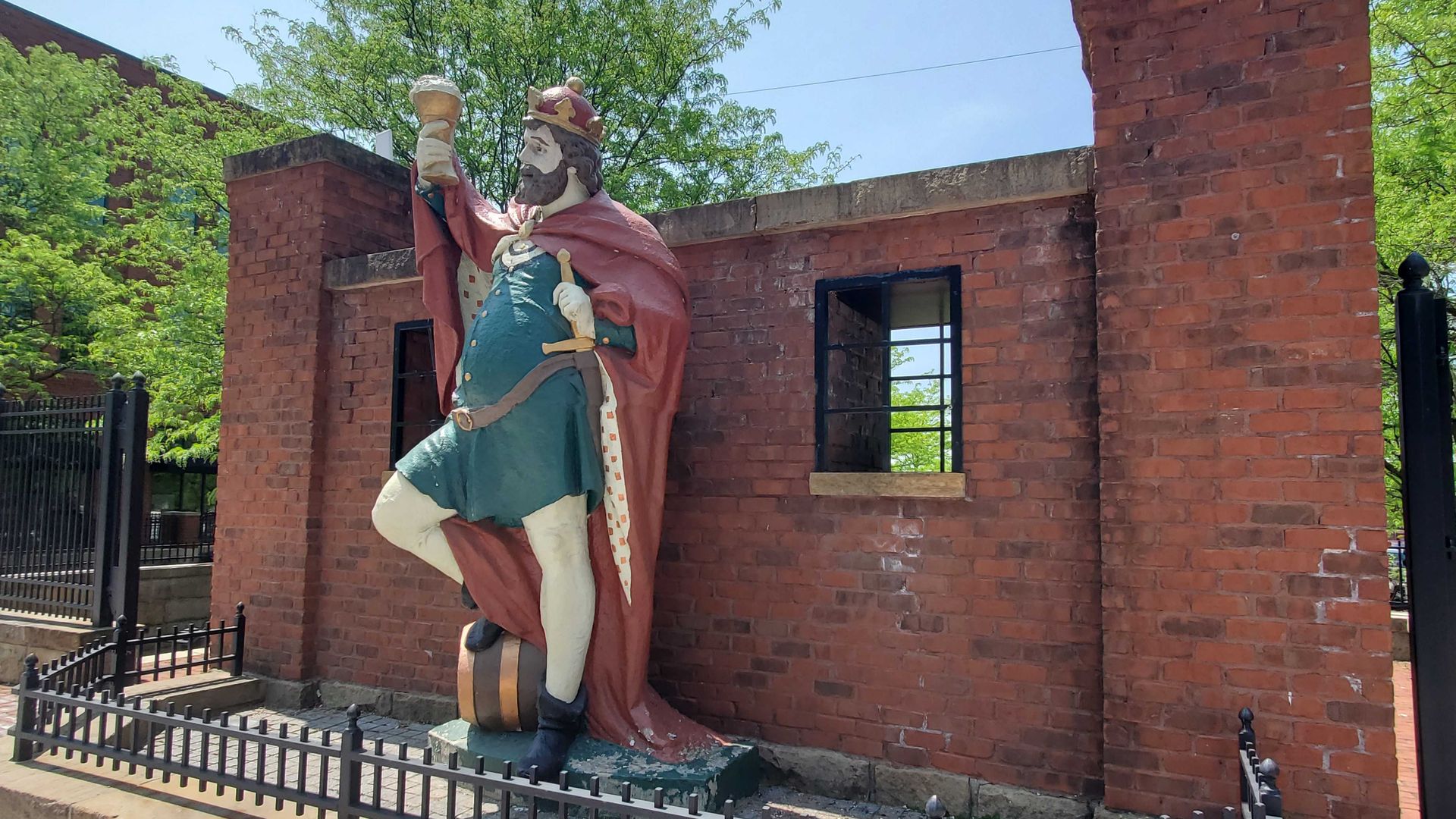 A statue of a portly king raising a beer.