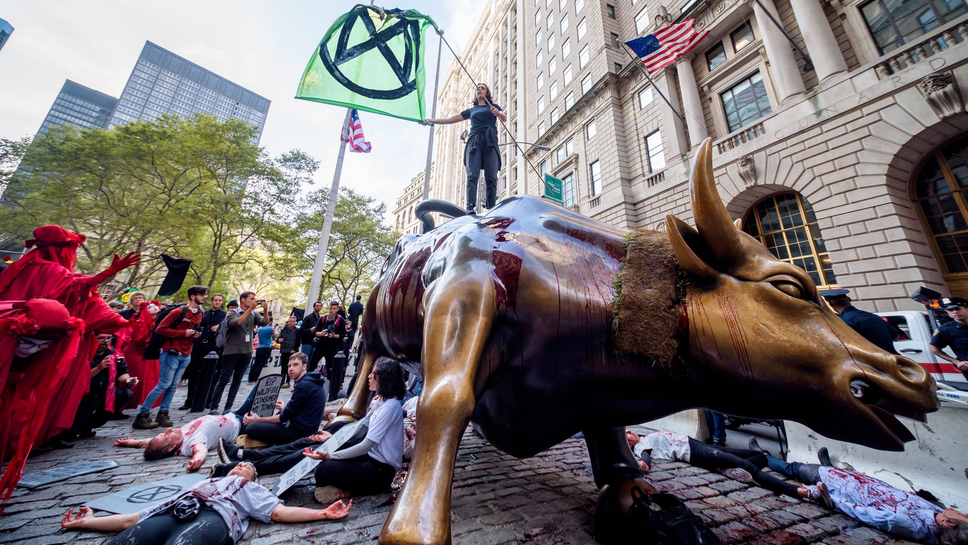 Photo of climate activist standing on top of the Wall Street bull during a protest in October 2019