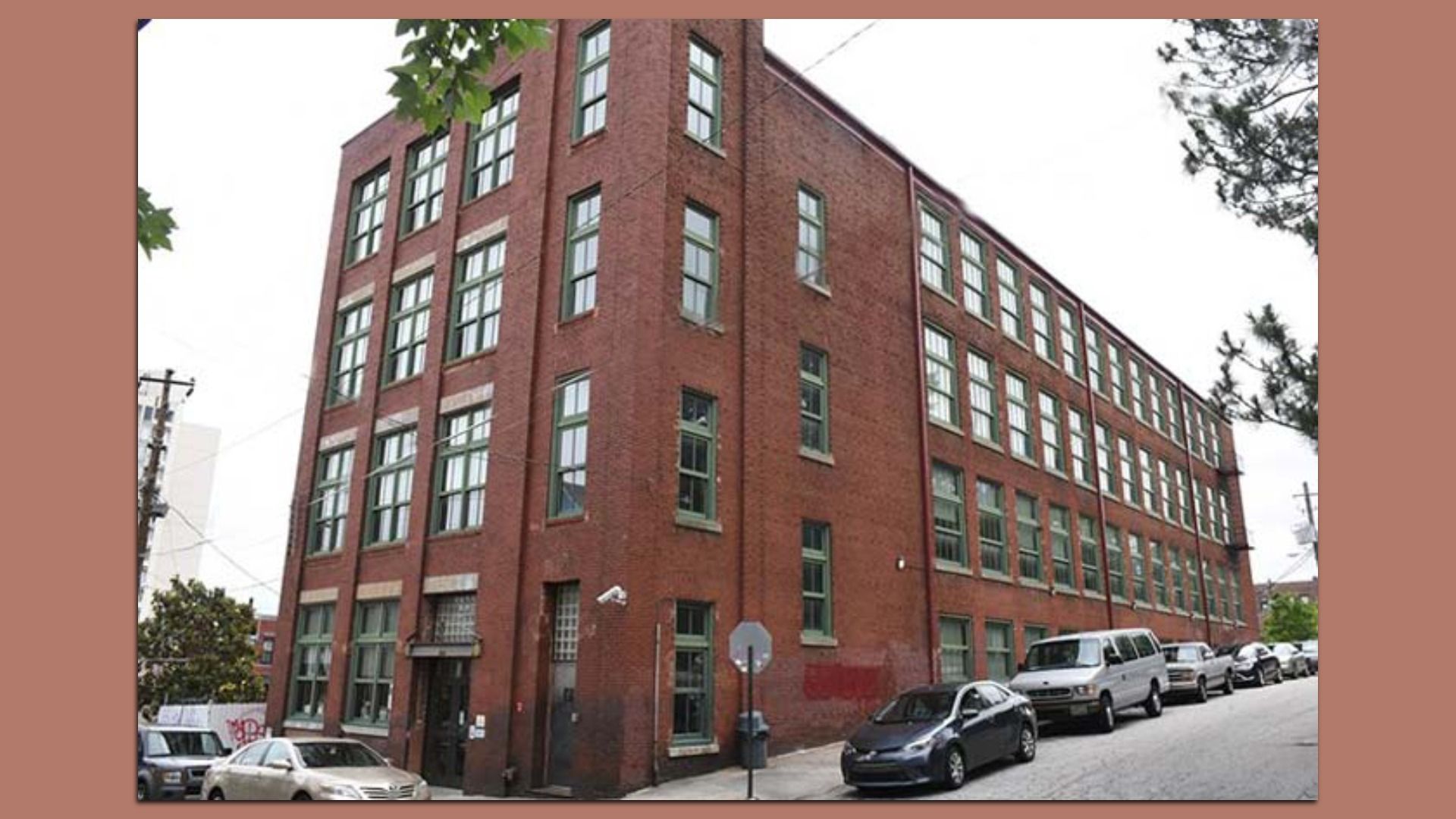 A red rectangular brick four-story building with green window frames.