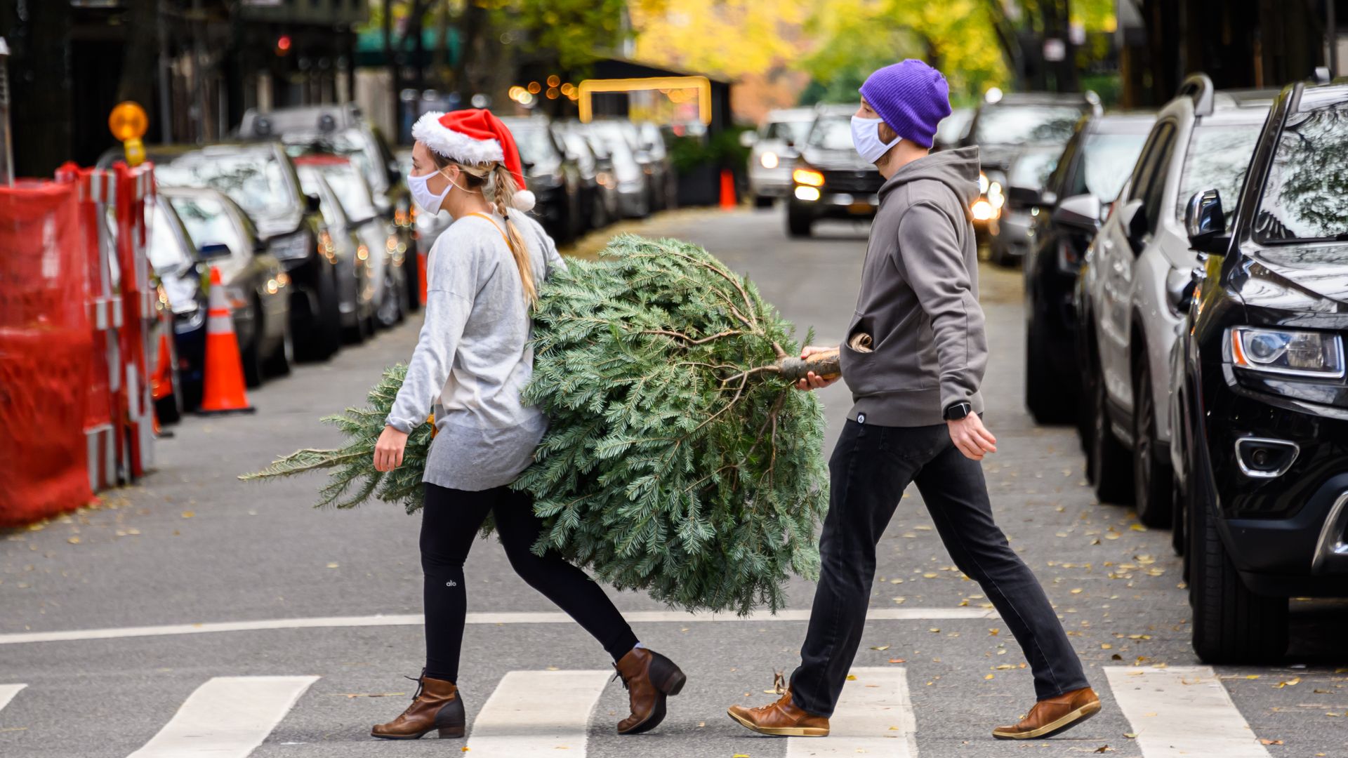 Two people carry a christmas tree through New York 