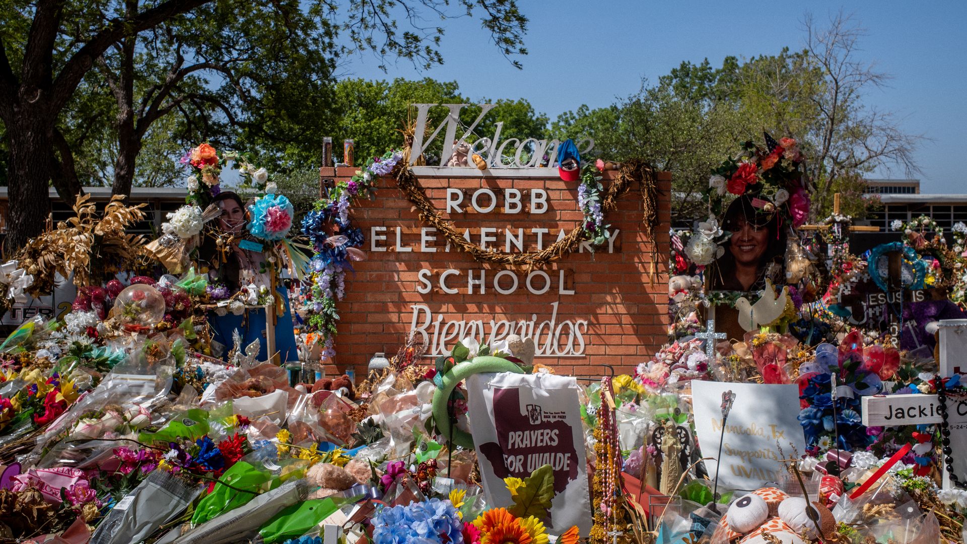 The outside sign for Robb Elementary School in Uvalde, TExas, is surrounded by flowers, balloons and signs in support of the shooting victims
