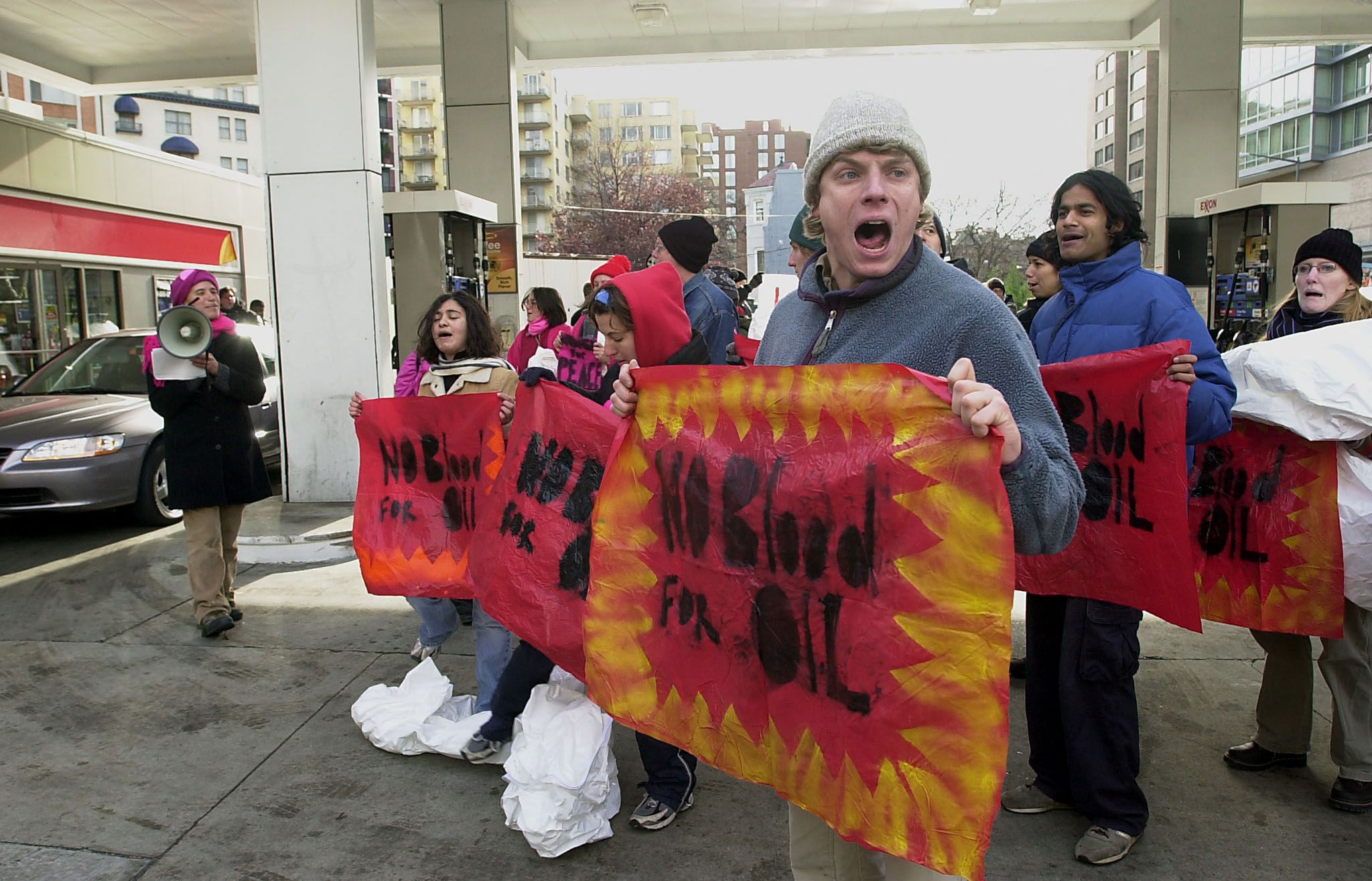 Protesters hold signs and chant outside an Exxon gas station in Washington, D.C., during a 2002 demonstration against a potential U.S. invasion of Iraq.