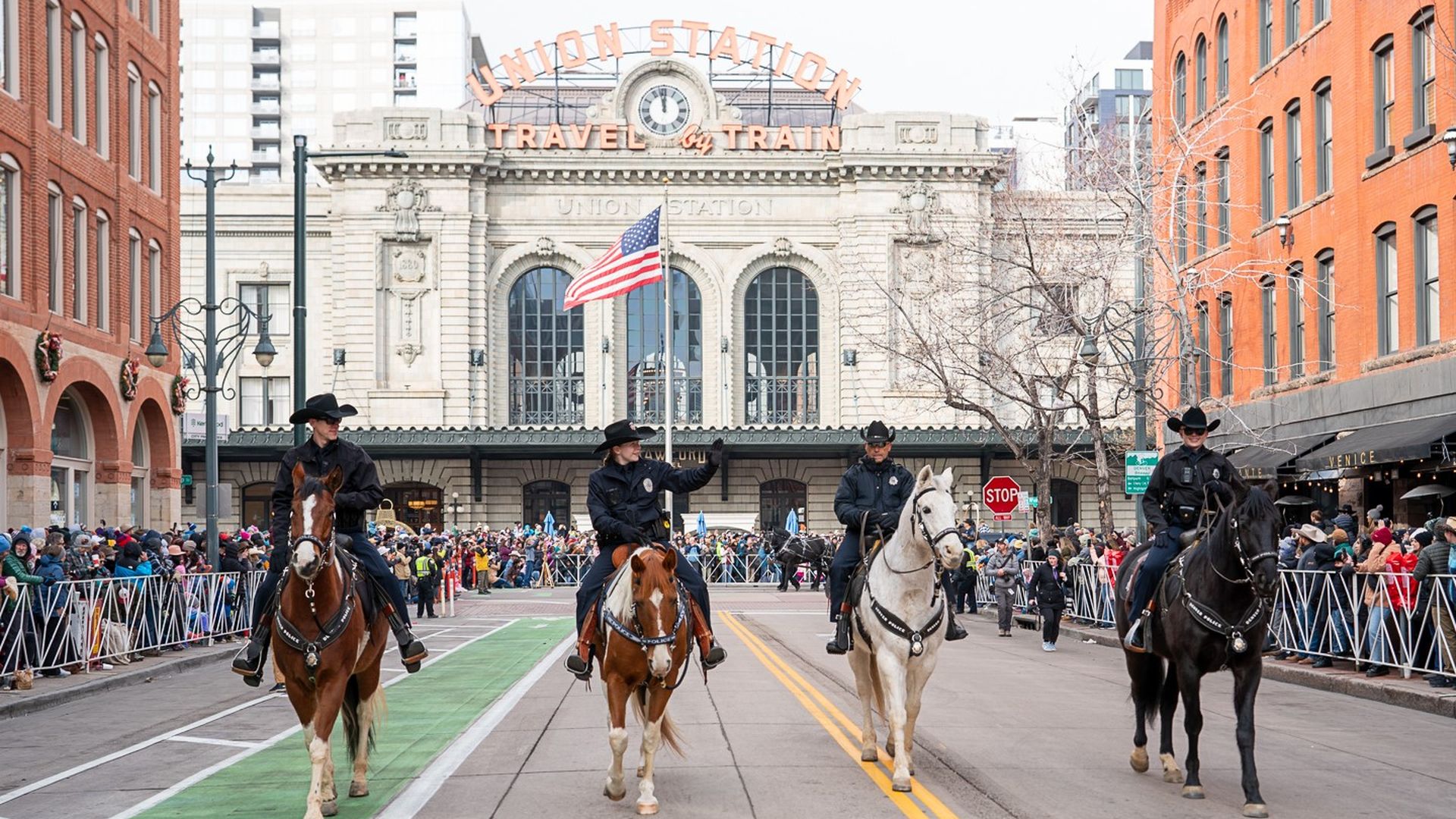A photo of four police officers leading a parade on horseback in front of Denver Union Station. 