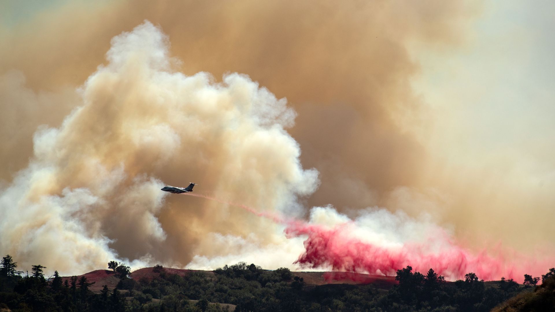 An aircraft helps fight the Saddleridge fire by dropping fire retardant along a ridge in Newhall, California on October 11, 2019