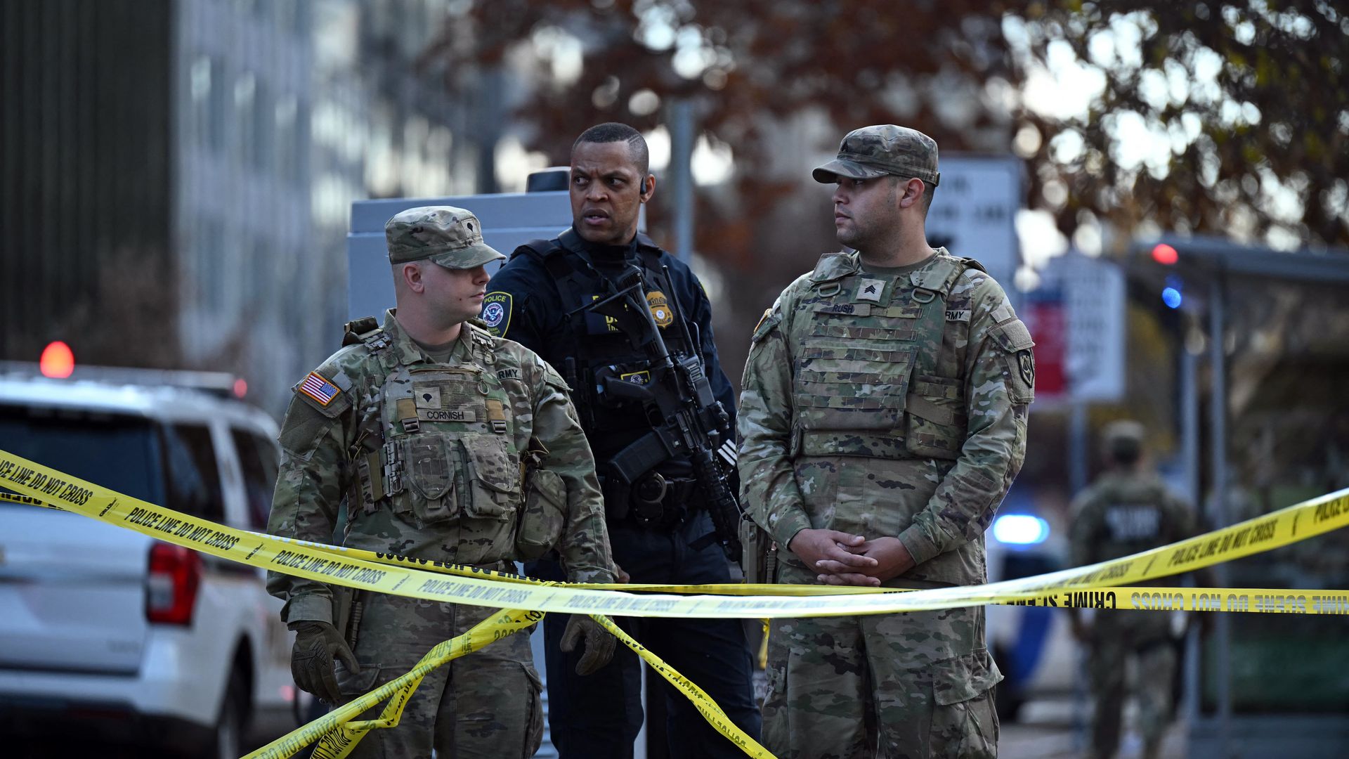 Two national guard soldiers and one police officer standing behind caution tape