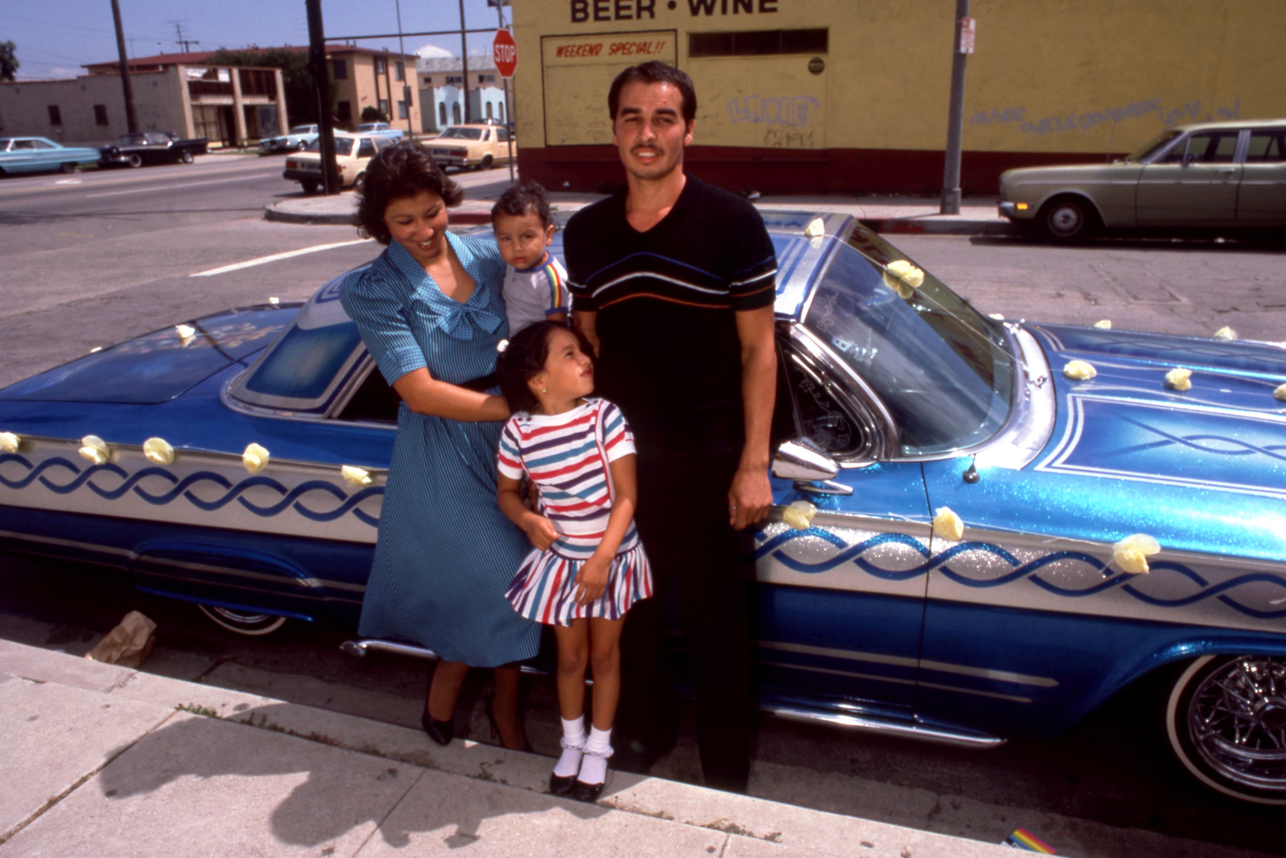 A Latino family poses for a portrait in front of their 1964 Chevy "Lowrider" Imapala circa August, 1983 in Los Angeles. 