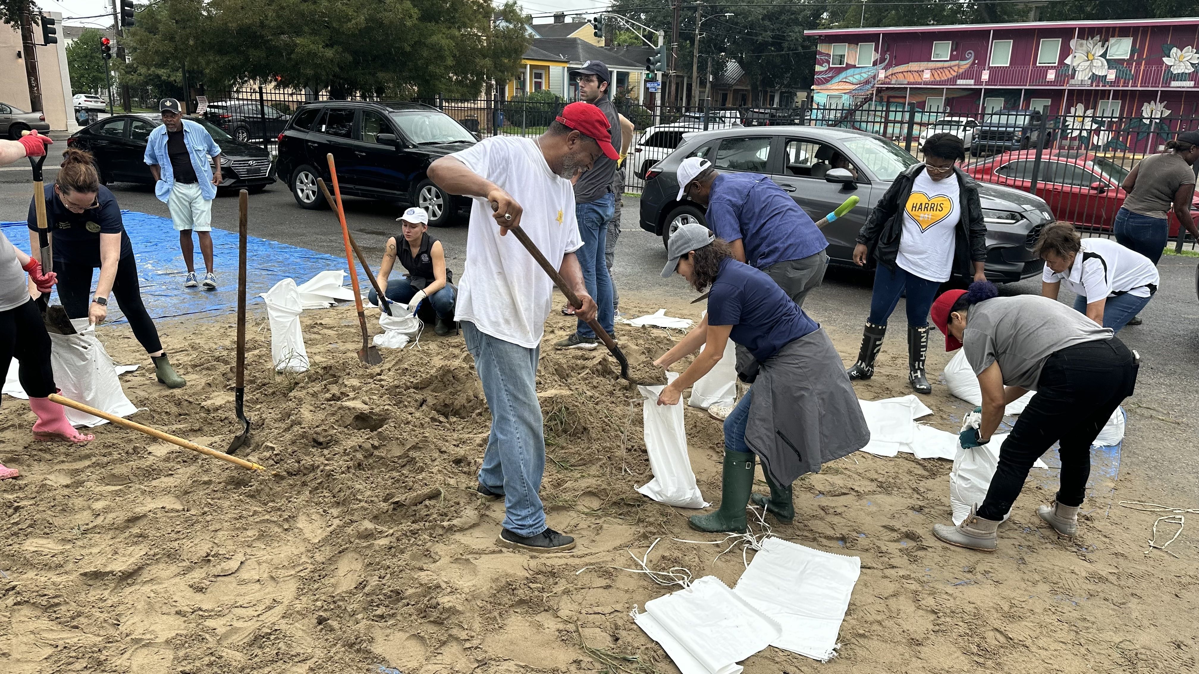 About a dozen people fill sandbags in a parking lot.