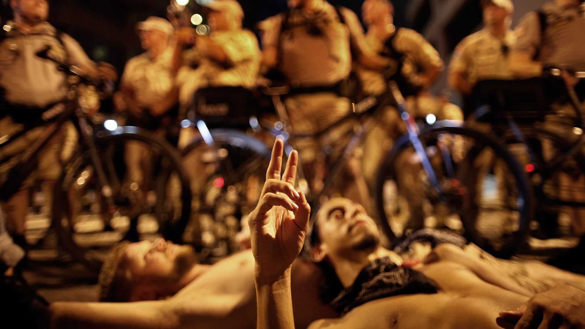 A protester flashes a peace sign while laying in the street during a protest march through downtown as the Republican National Convention wraps up at the Tampa Bay Times Forum.