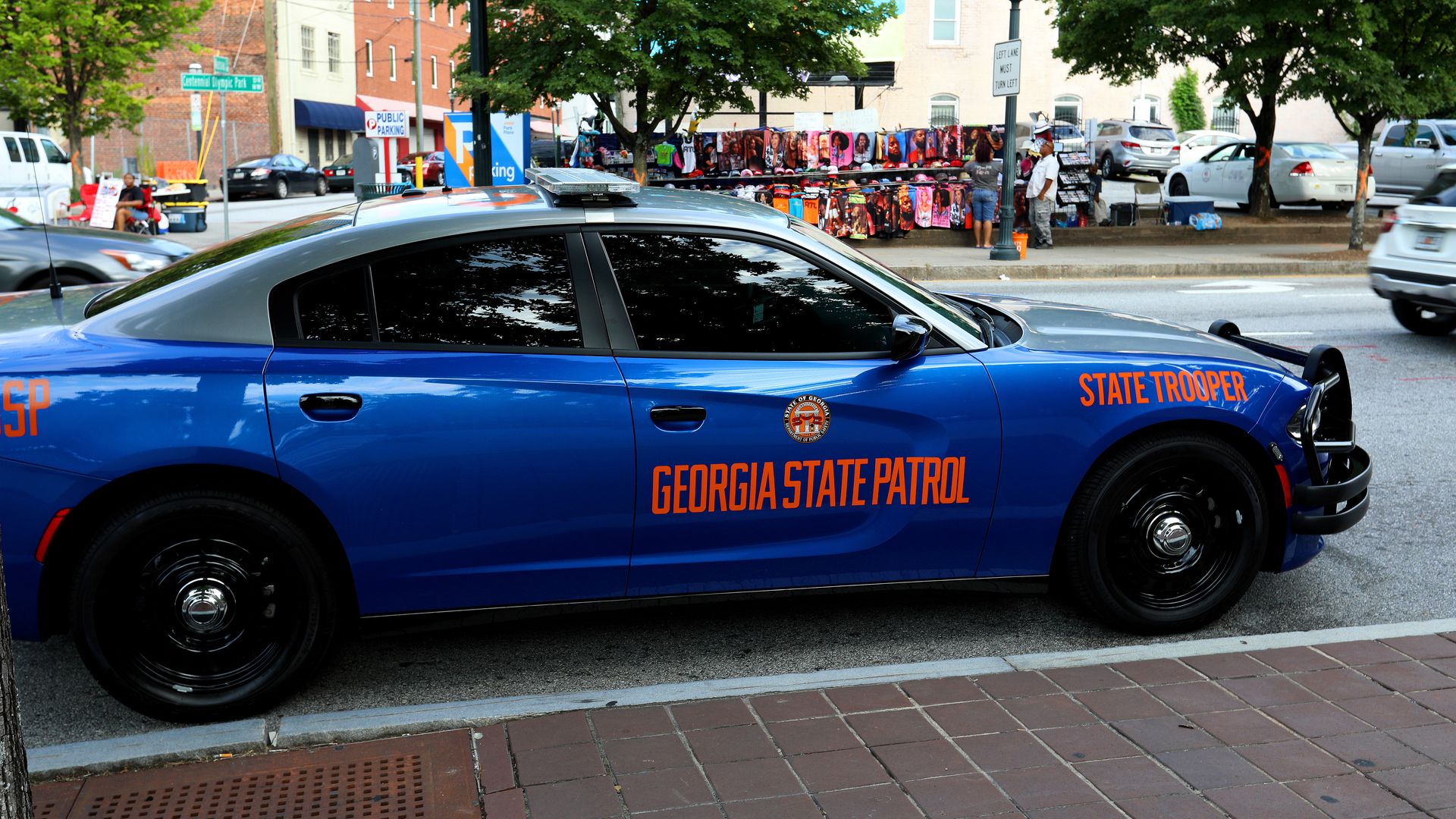 A blue law enforcement Dodge Charger that says "Georgia State Patrol" is parked alongside a curb