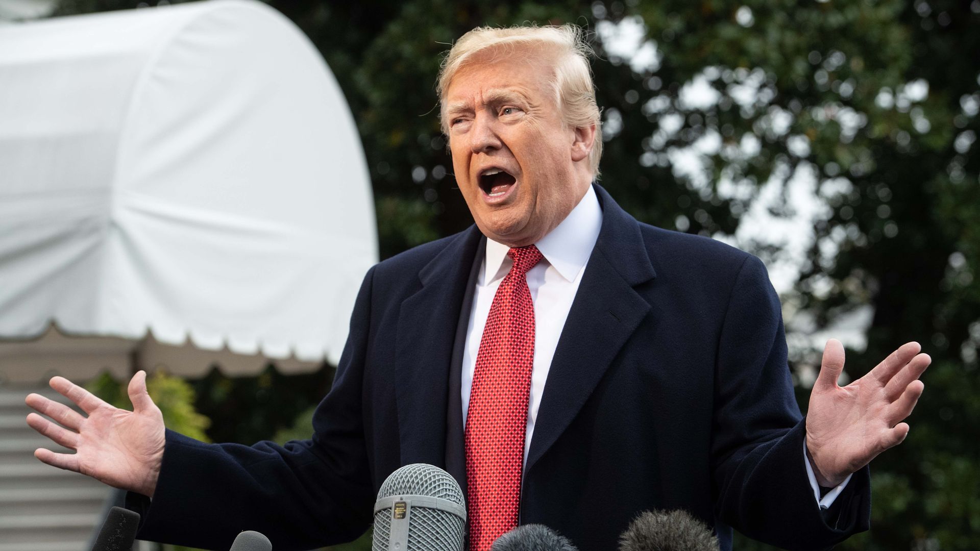 Donald Trump shouting at the press with both hands up.