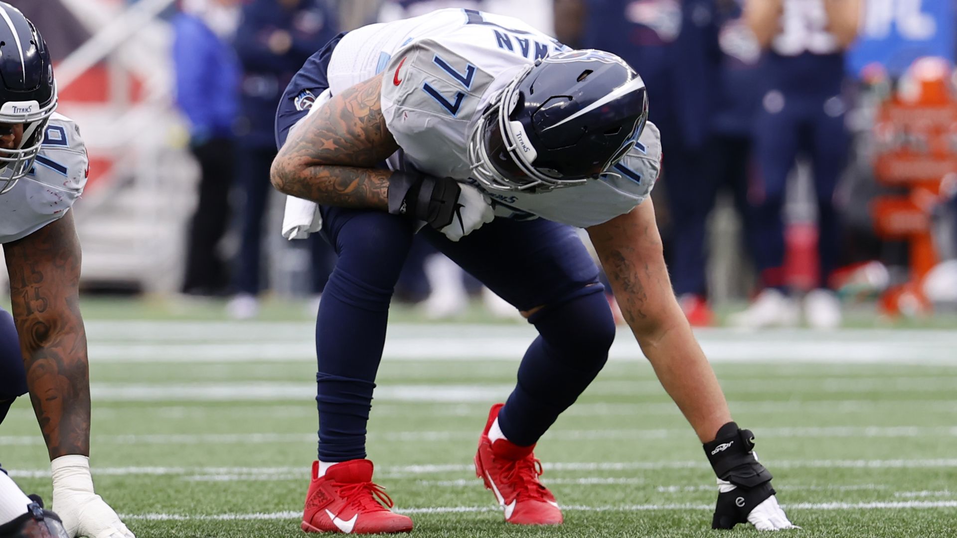 Tennessee Titans offensive tackle Taylor Lewan crouches on a football field.